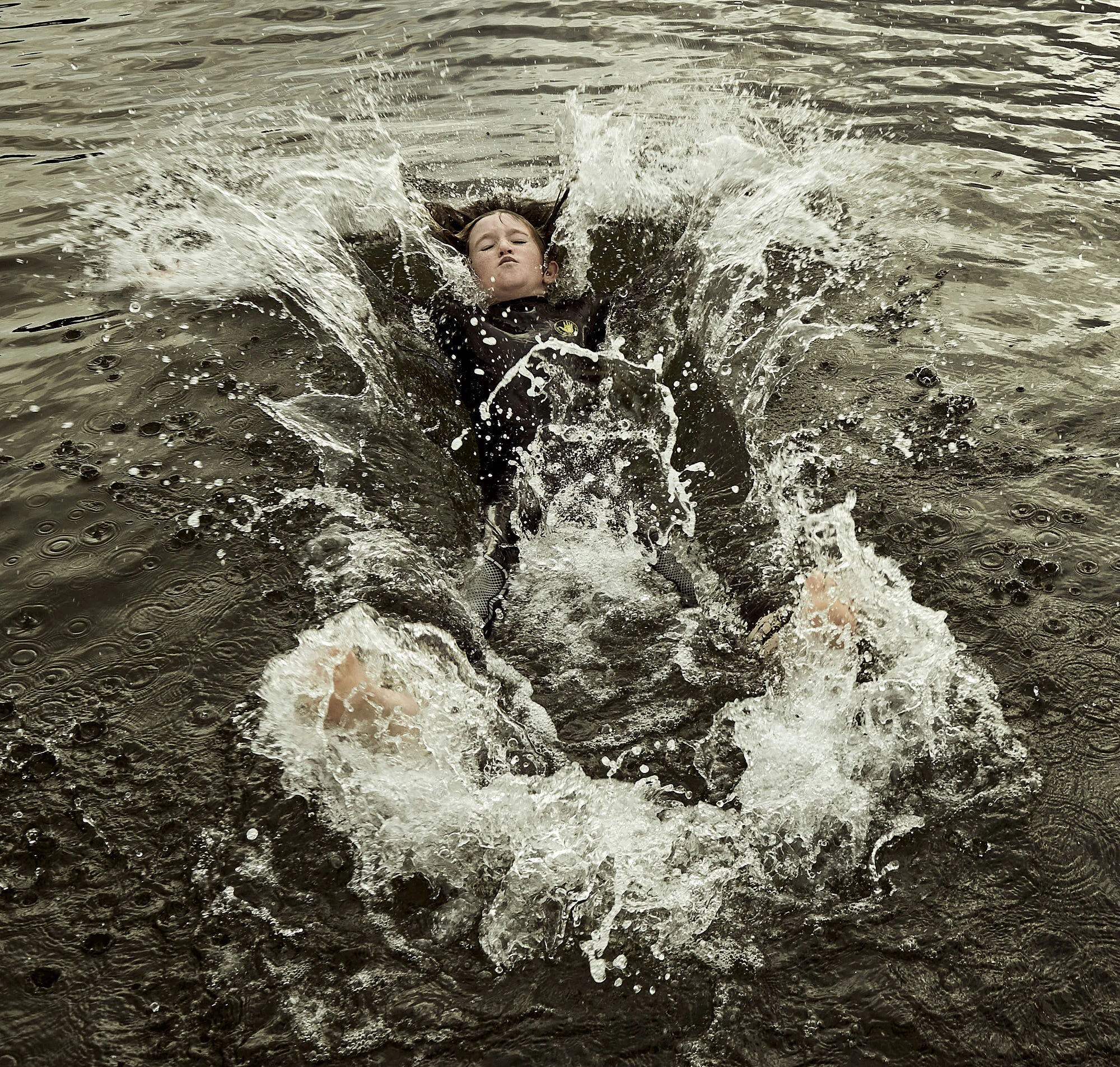 A person swimming in a body of water, causing splashes and waves around them.