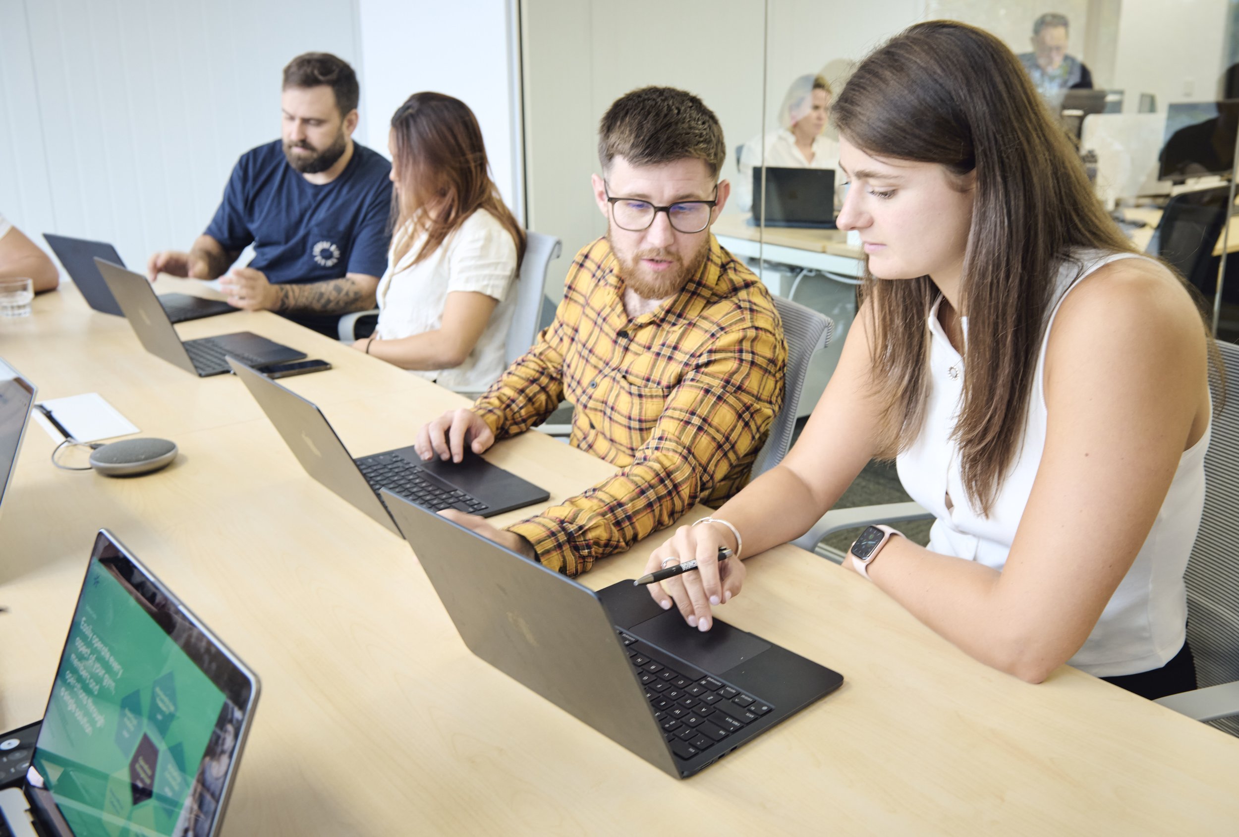 Business meeting with employees working on laptops at a conference table in an office.