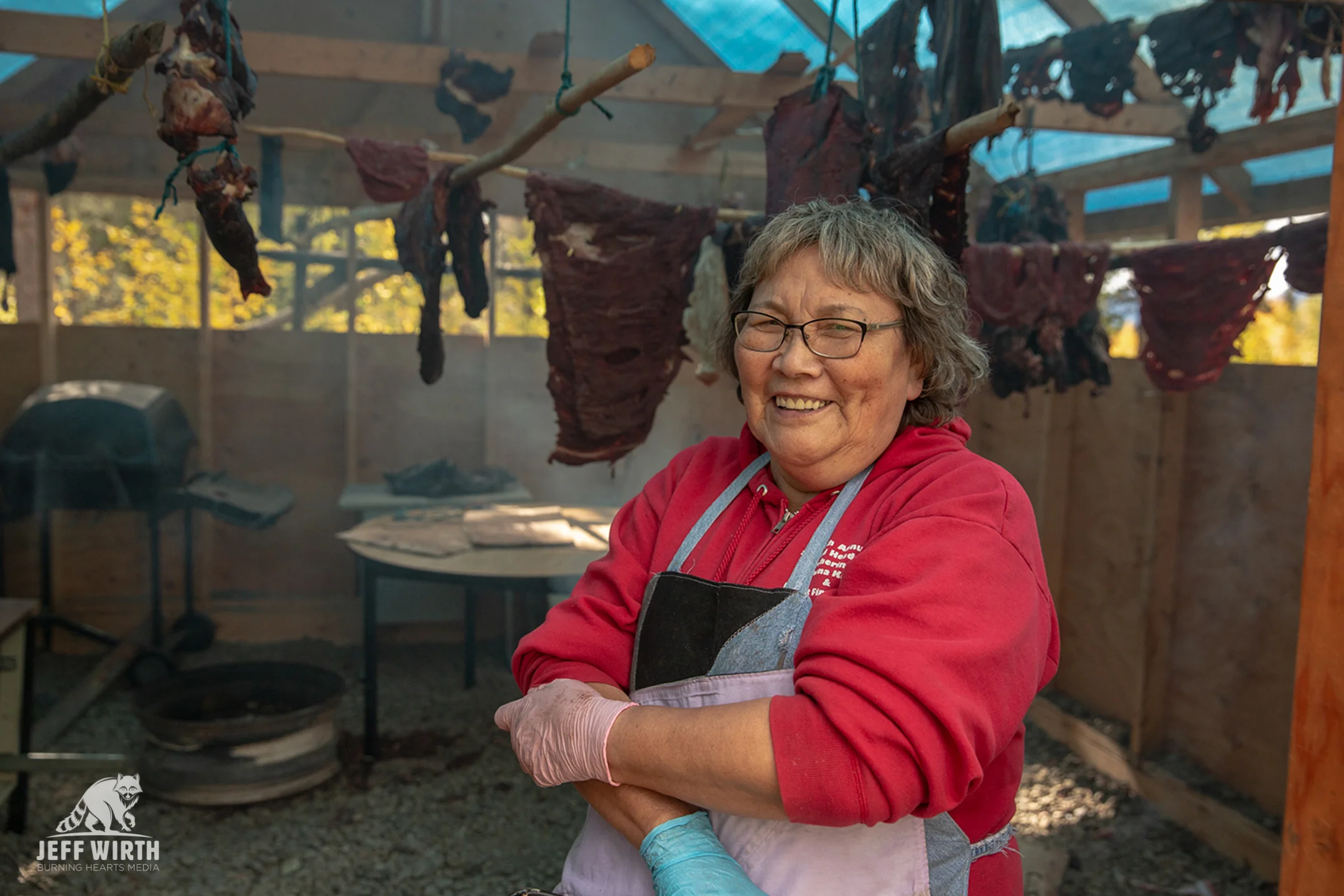 Tahltan / Klabona Keeper elder Bertha Louie poses and gives a smile in front of the community smoke house near the community of Iskut. Sacred Headwaters, BC, Canada.