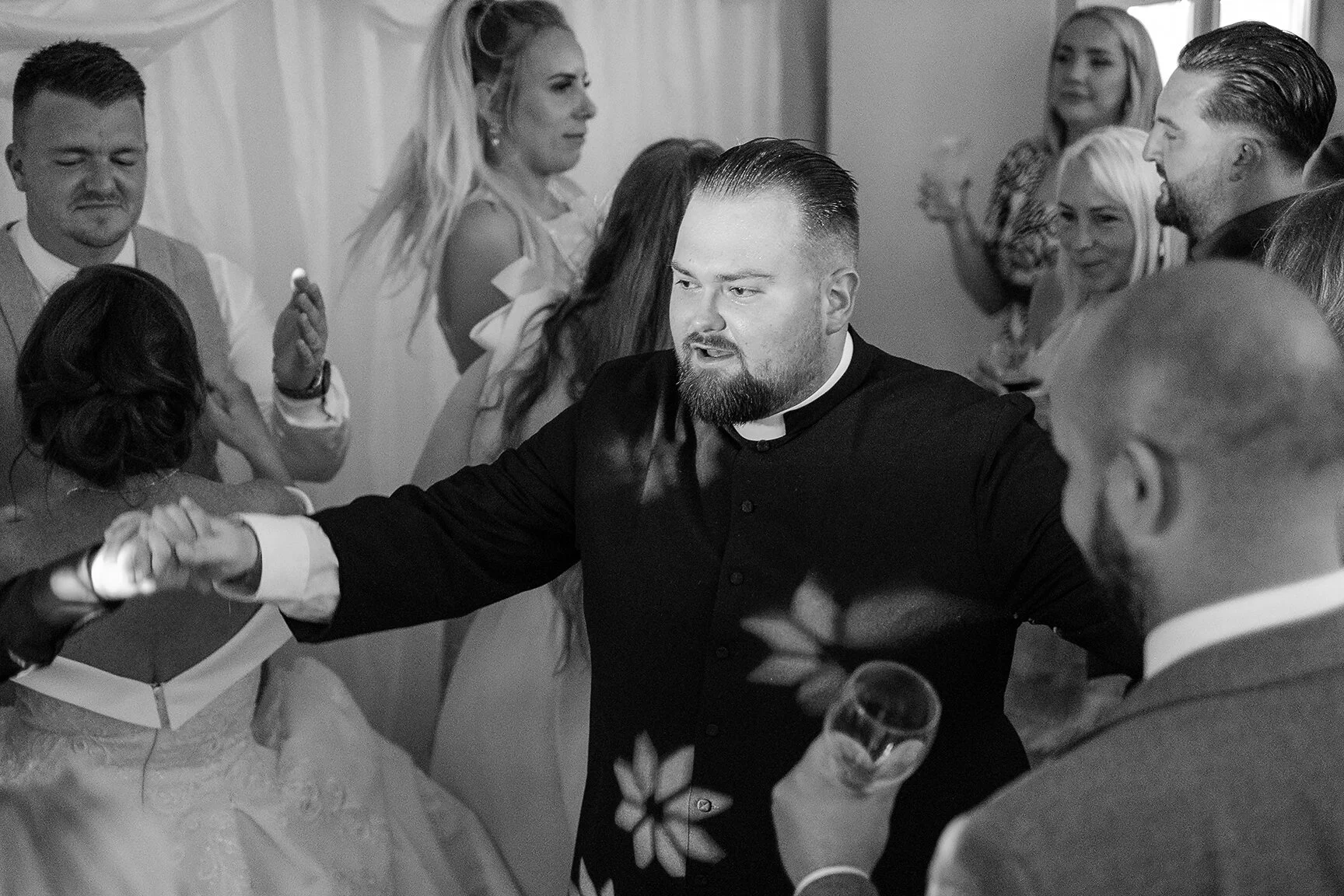 Vicar priest photographed dancing at a wedding reception in a documentary candid style