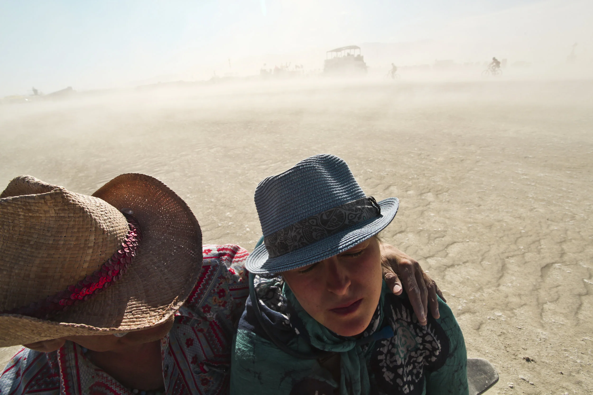  Impulse and April both second year burners shield themselves from a dust storm while sitting in the middle of the playa. People wear goggles and dust masks to help prevent themselves from getting dust into their orifices. 