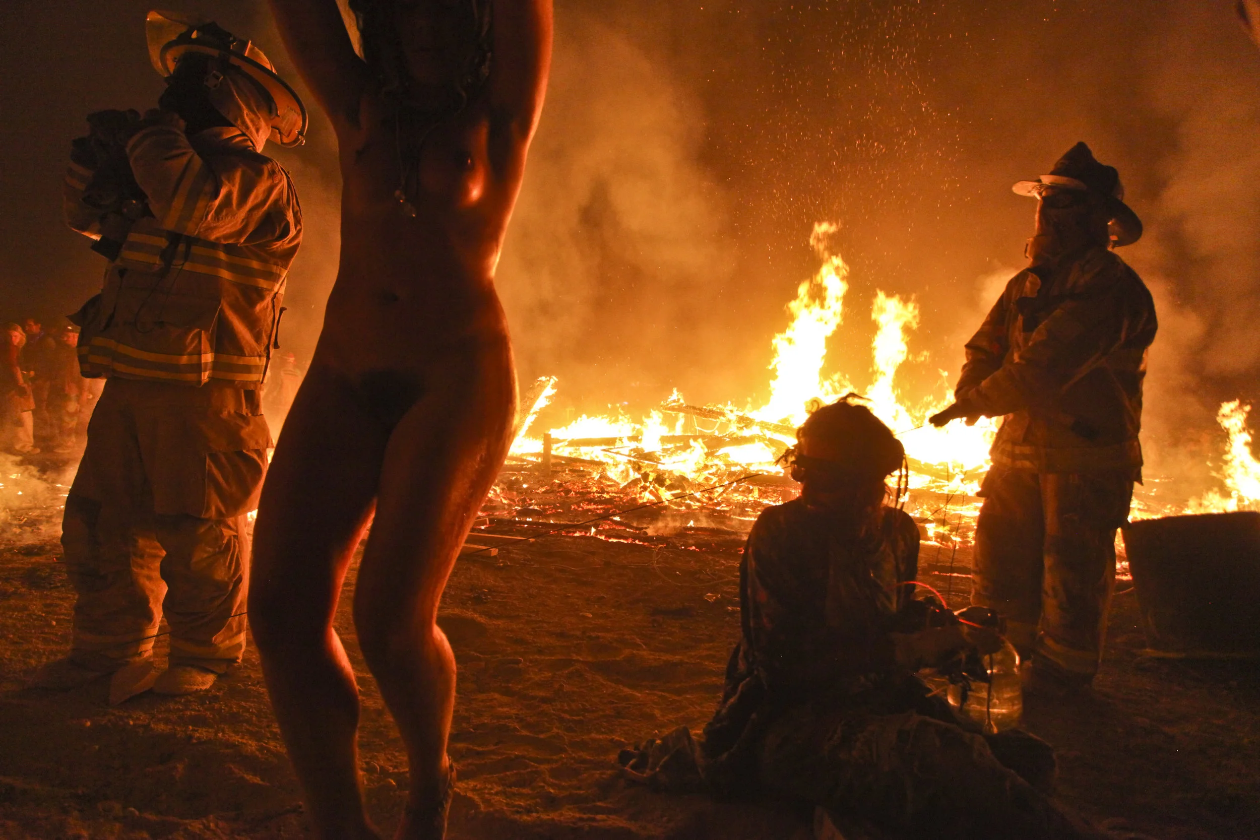  After the mans structure has burnt completely to the ground, the thousands of people surrounding the man then come rushing in towards the fire. 