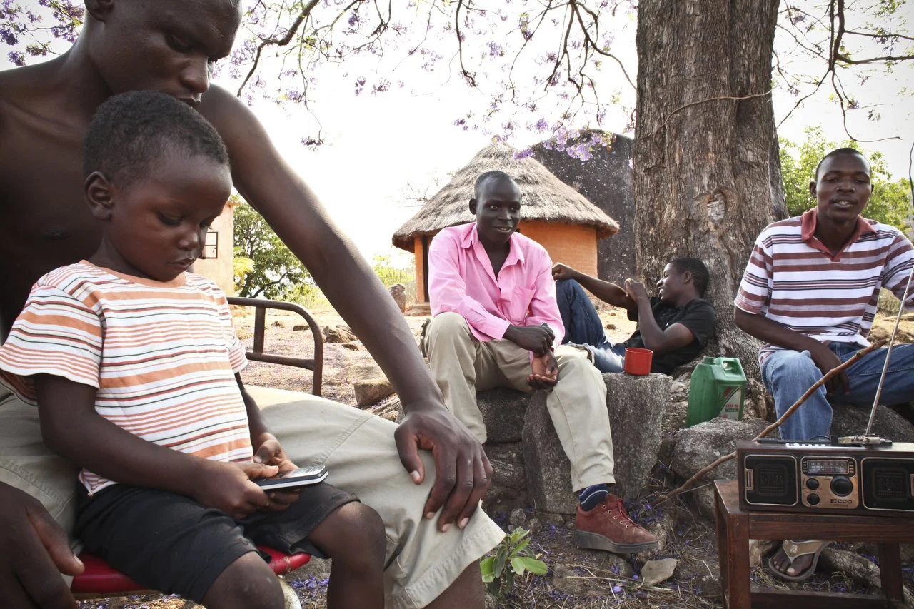  Reymond Mapakata , sits under a Jacaranda tree with is son and friends in his village which is located in the region of Bakita in Zimbabwe. Raymond left his home to seek "greener pastures" in South Africa. The village is about a 40 minute hike from 