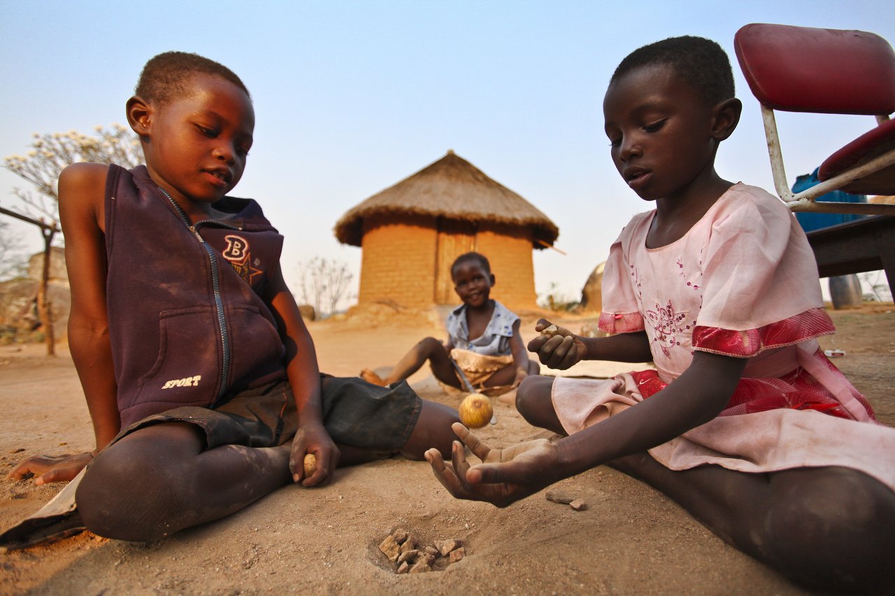  Kids play a game with rocks and a fruit fallen from a tree outside their home in the region of Bakita in Zimbabwe. The village is about a 40 minute hike from the closest shops. Thousands of Zimbabwean refugees crossed the border to South Africa to e