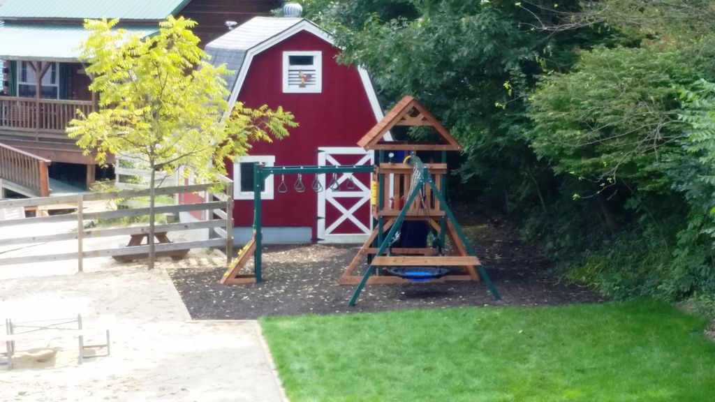 Playscape has 2 lisdes, monkey bars, rock climb wall, swings - in view of deck.