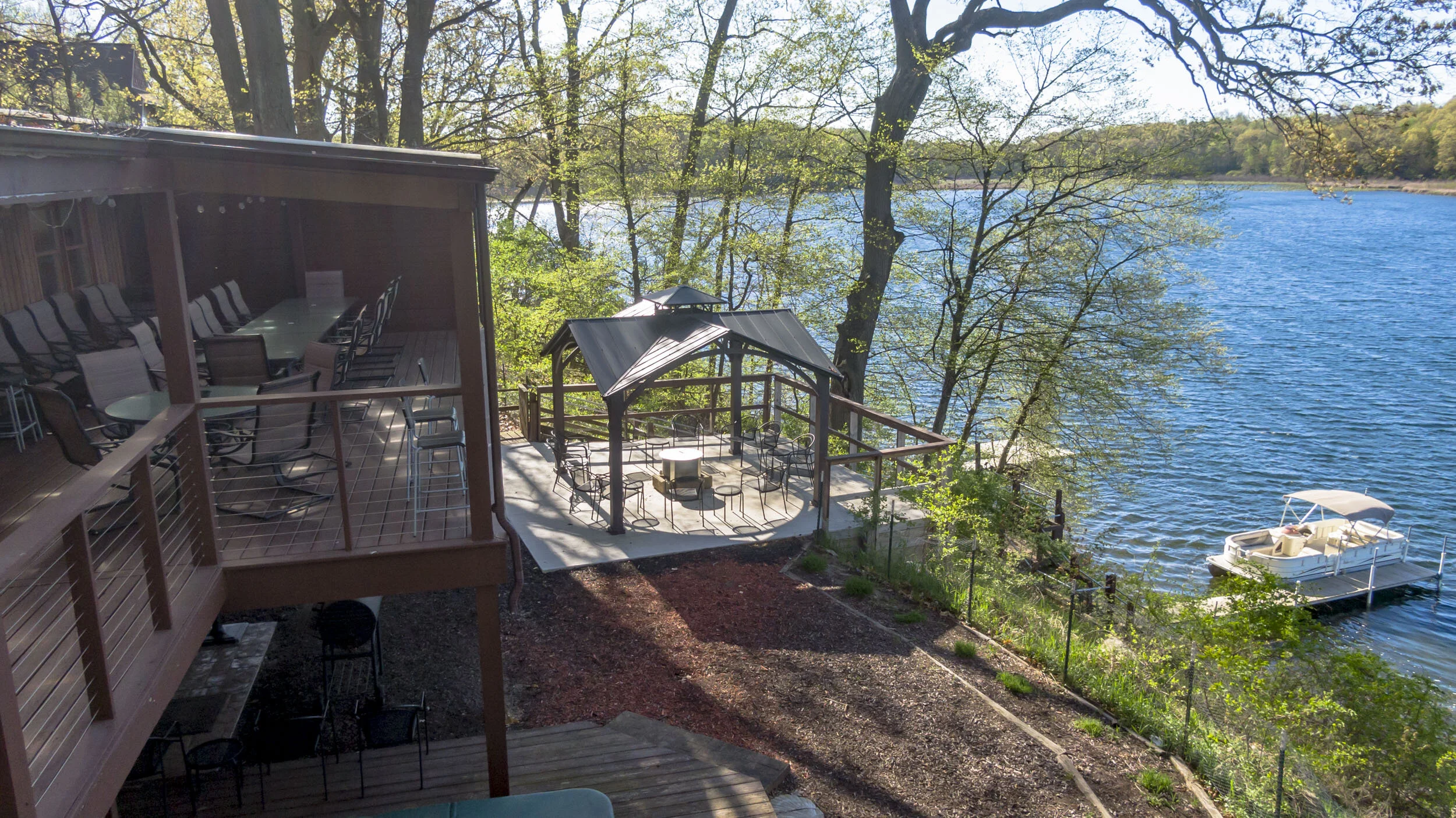 Gorgeous view of the deck & fire pit overlooking Stone Lake and the boat dock.
