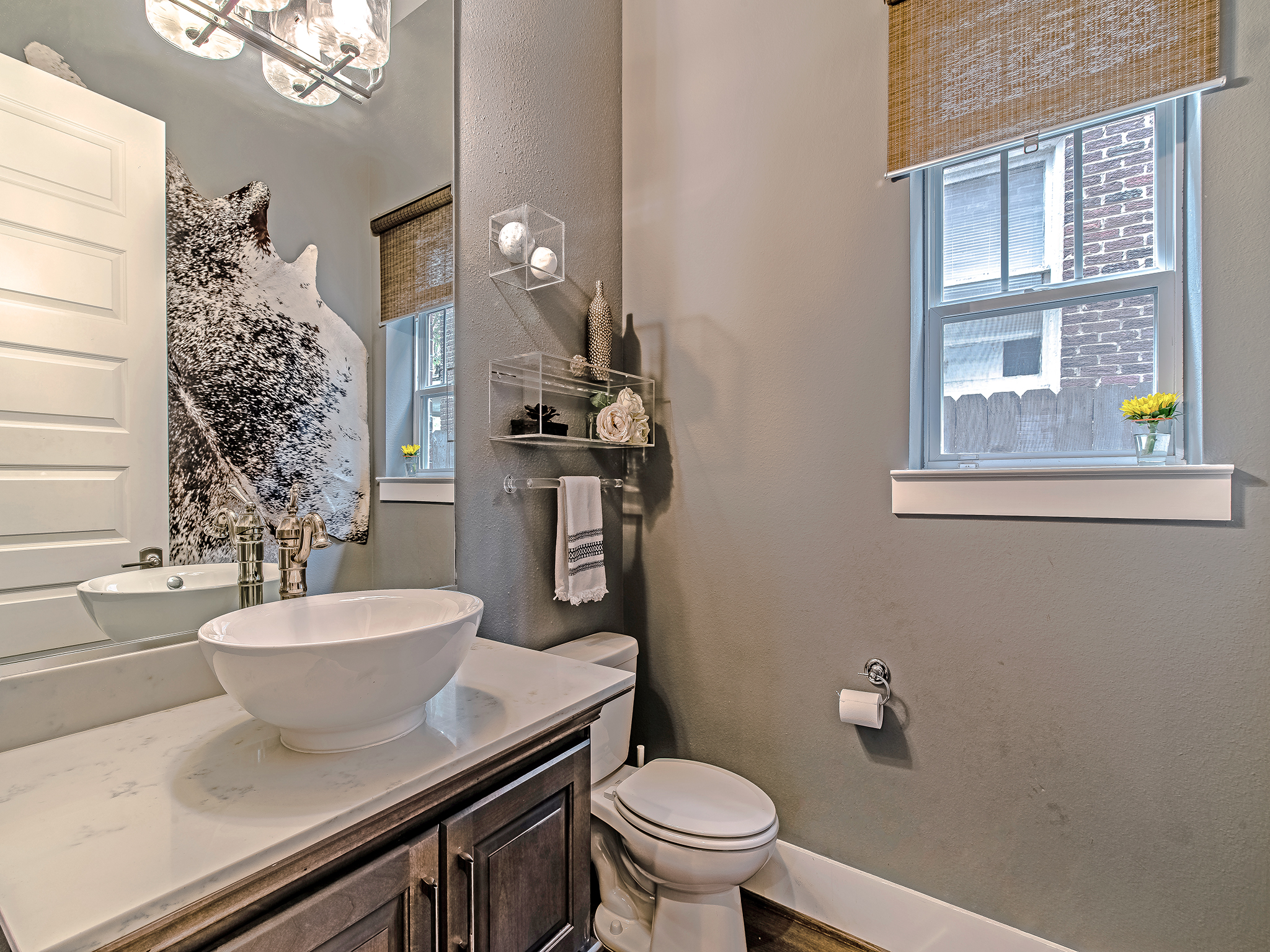 First floor powder room features a vessel sink and woven shades.