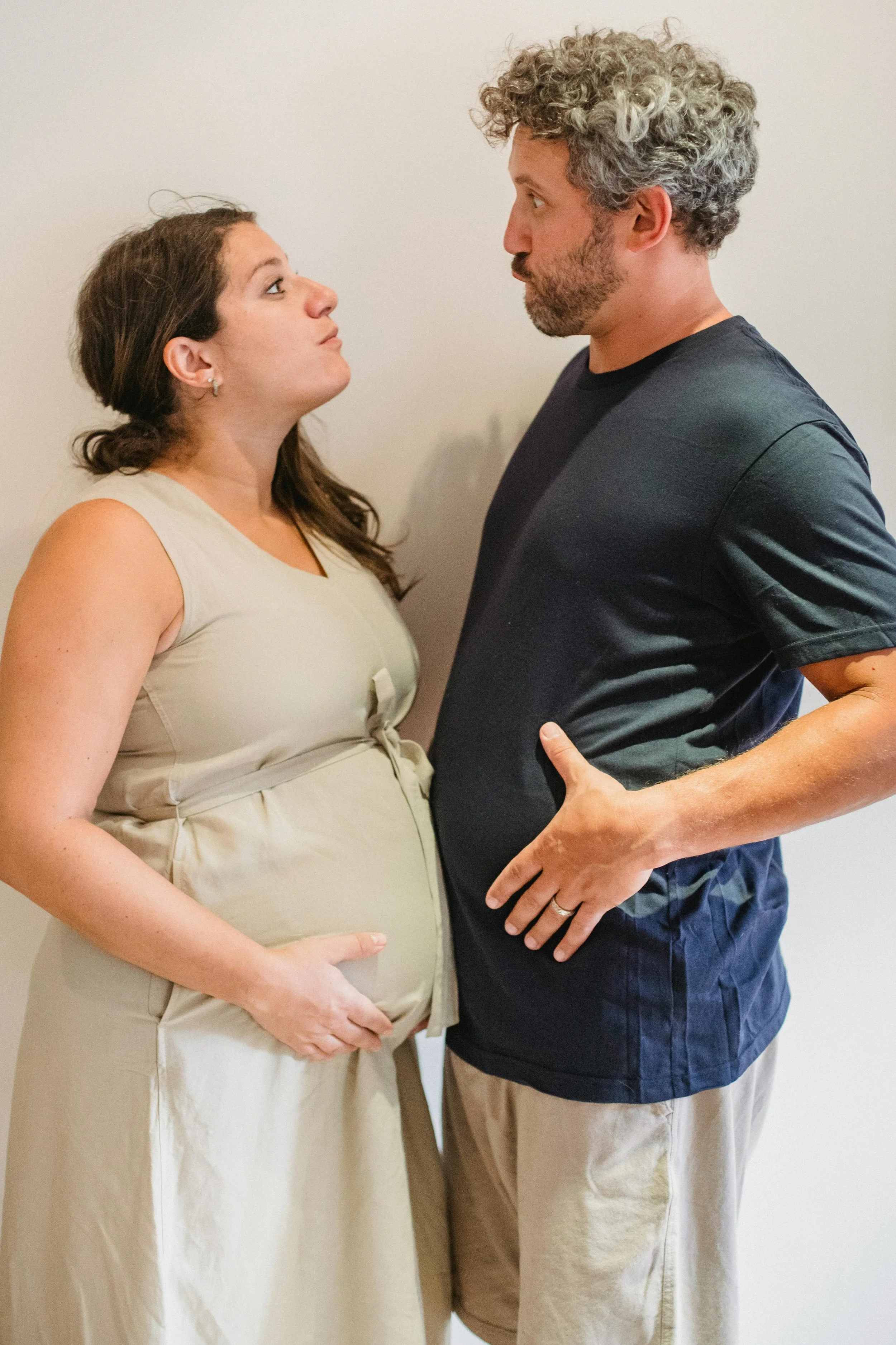 Pregnant woman and her partner facing each other with hands near her belly, representing fertility and prenatal support at South Shore Acupuncture and Wellness, Rockland MA.