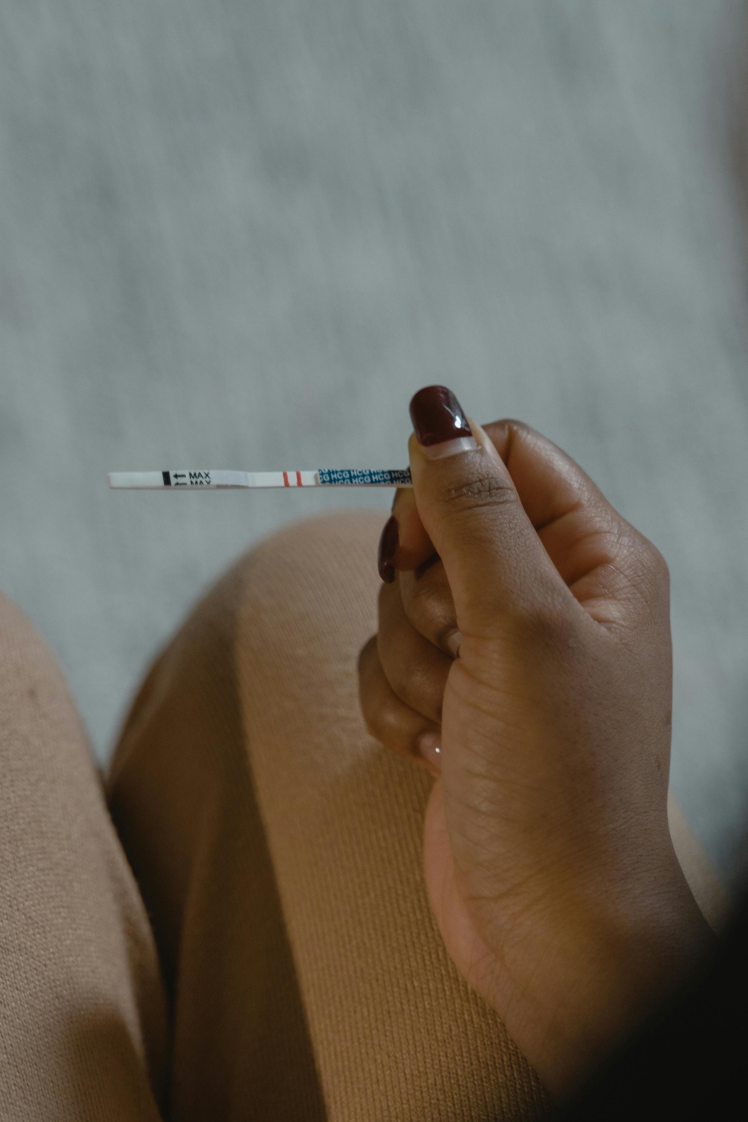 A woman holding an ovulation testing strip, representing the role of stress and nervous system regulation in ovulation and fertility at South Shore Acupuncture and Wellness, Rockland MA.