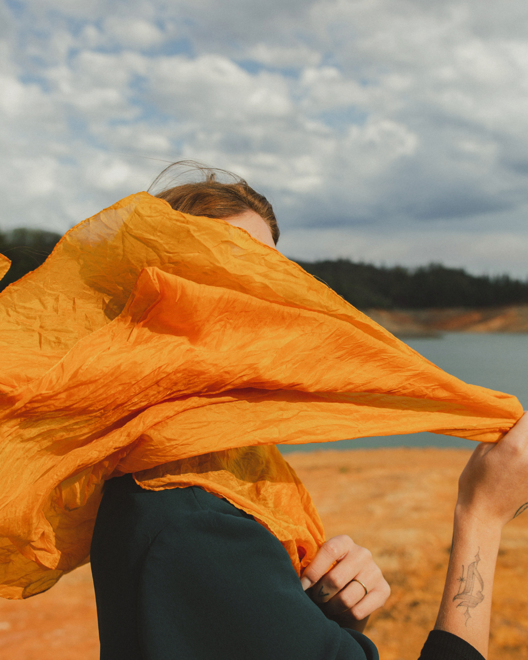 Woman holding an orange veil partially covering her face, symbolizing facial paralysis and Bell’s Palsy recovery