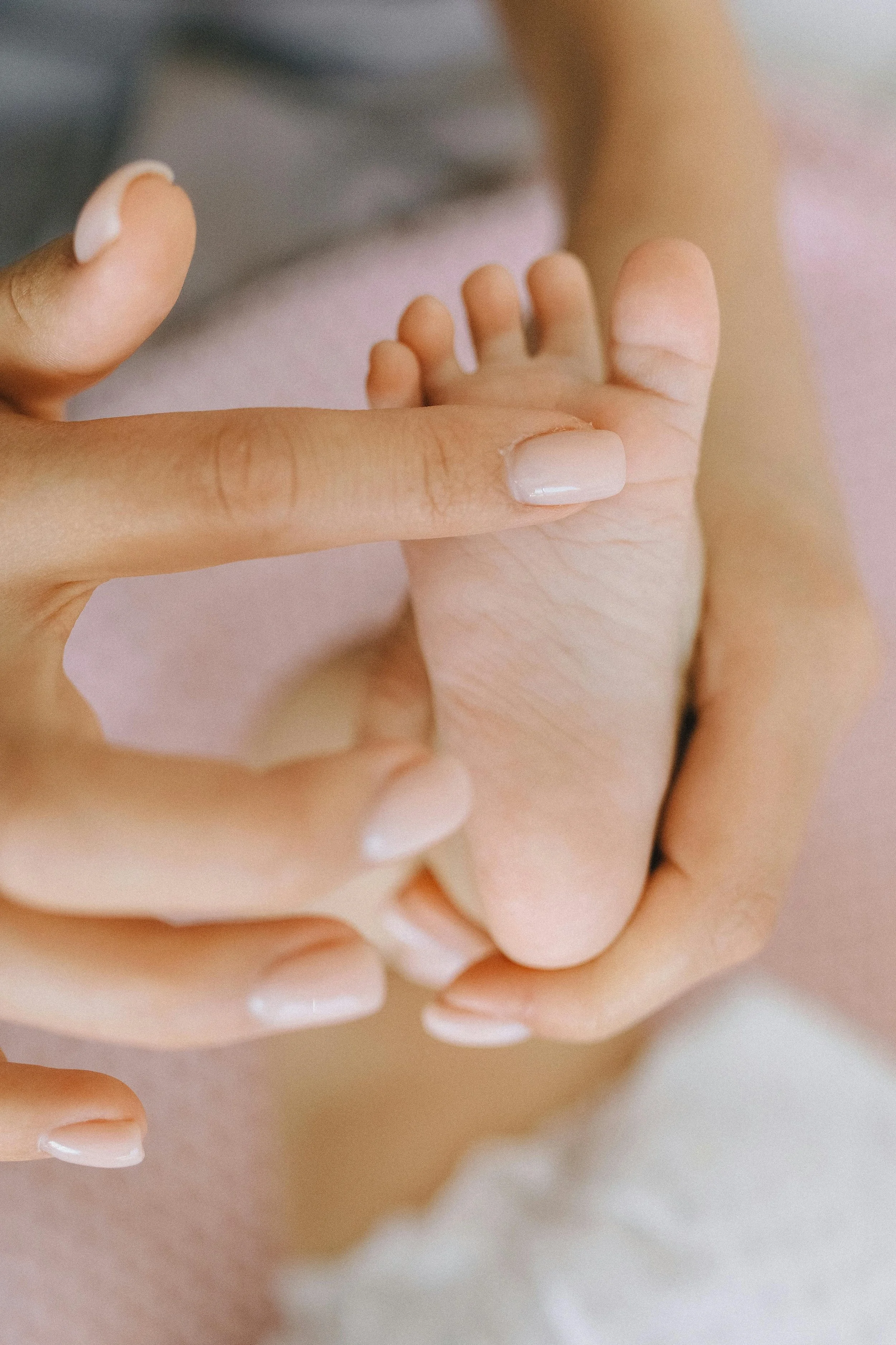 A mother's hands cradling a newborn's tiny foot, representing third trimester and birth preparation support at South Shore Acupuncture and Wellness, Rockland MA.