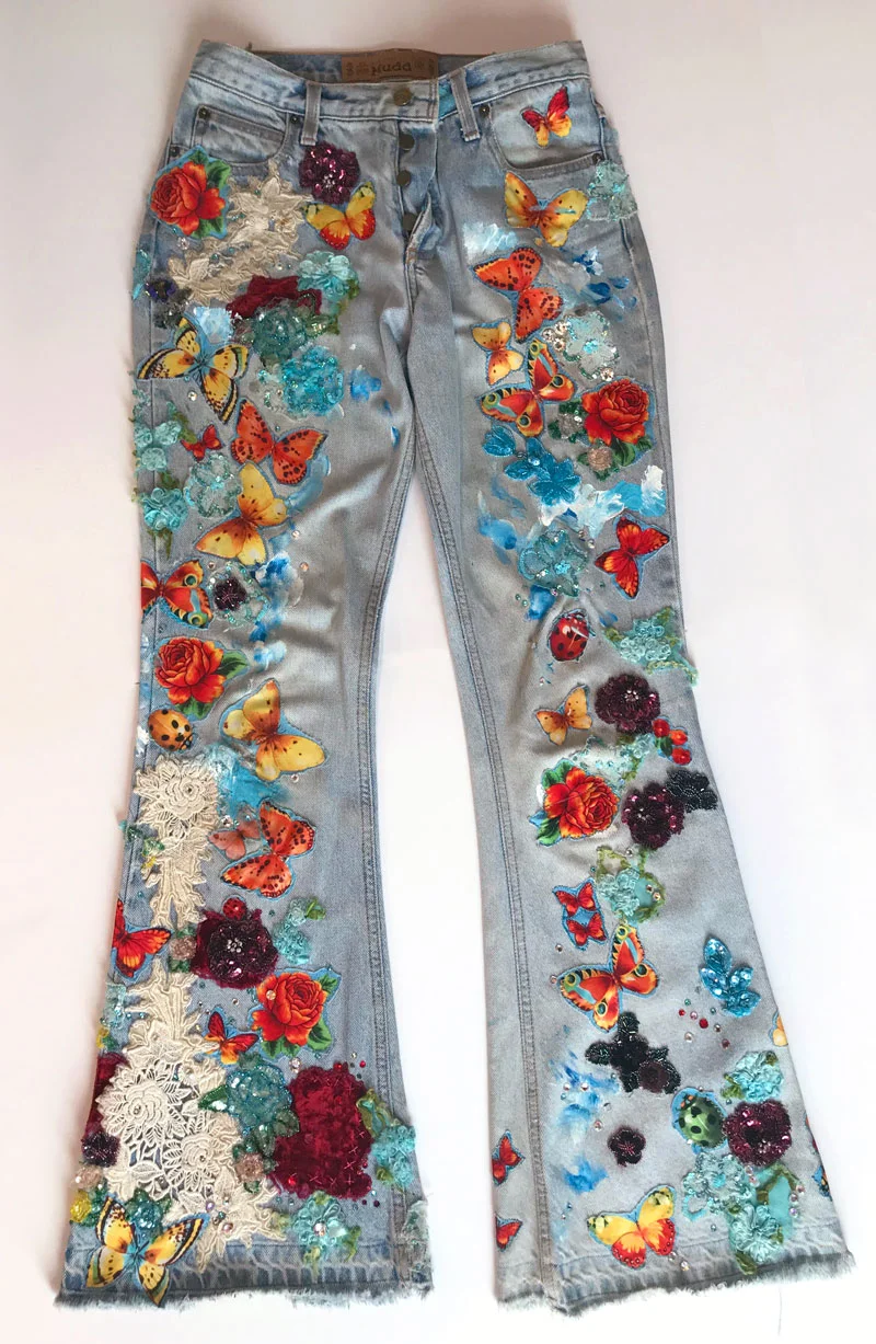 Hand-applied flower print fabric, sequin patches, Swarovski crystals, paint, vintage lace, and embroidery on denim jeans.