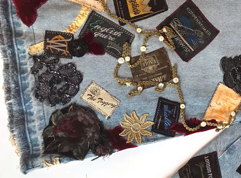 Detail of back. Vintage men’s suit labels, gold trims, buttons, vintage measuring tapes on denim jeans.