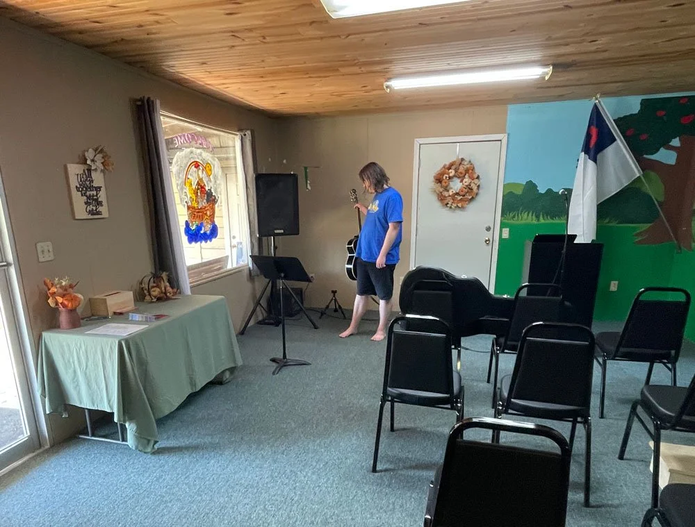 Man putting guitar on a stand in temporary church sanctuary