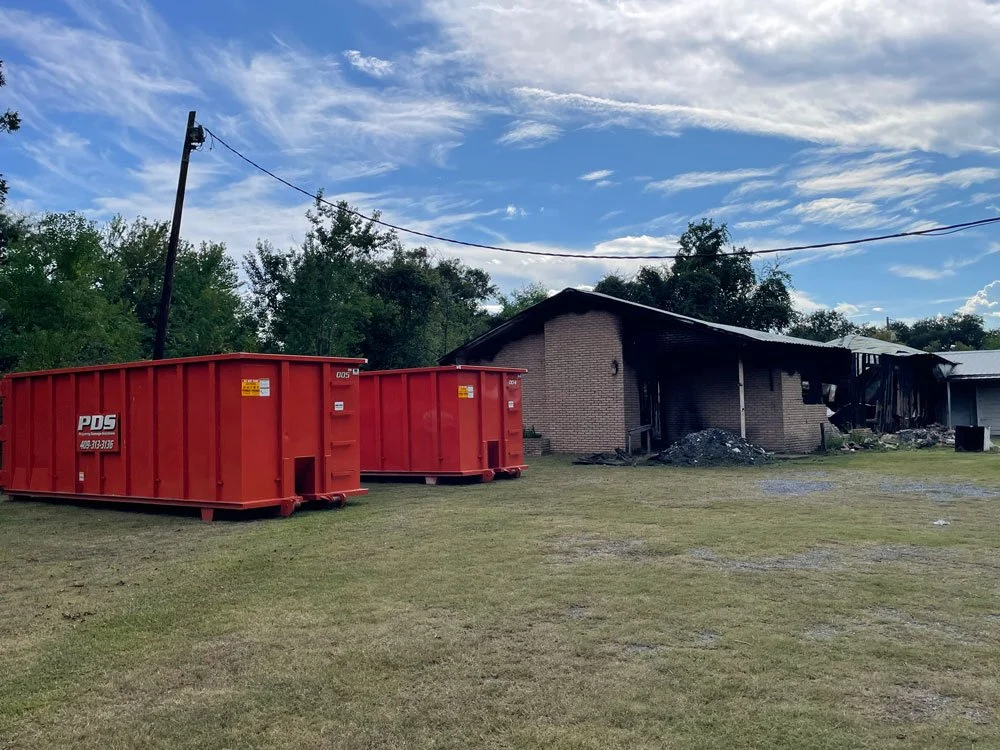 2 large orange dumpsters in front of burned sanctuary building