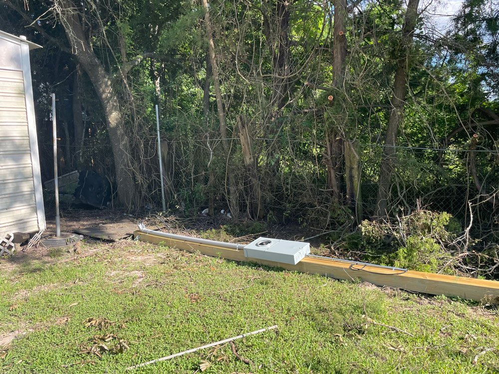 electric pole laying on ground in front of treeline