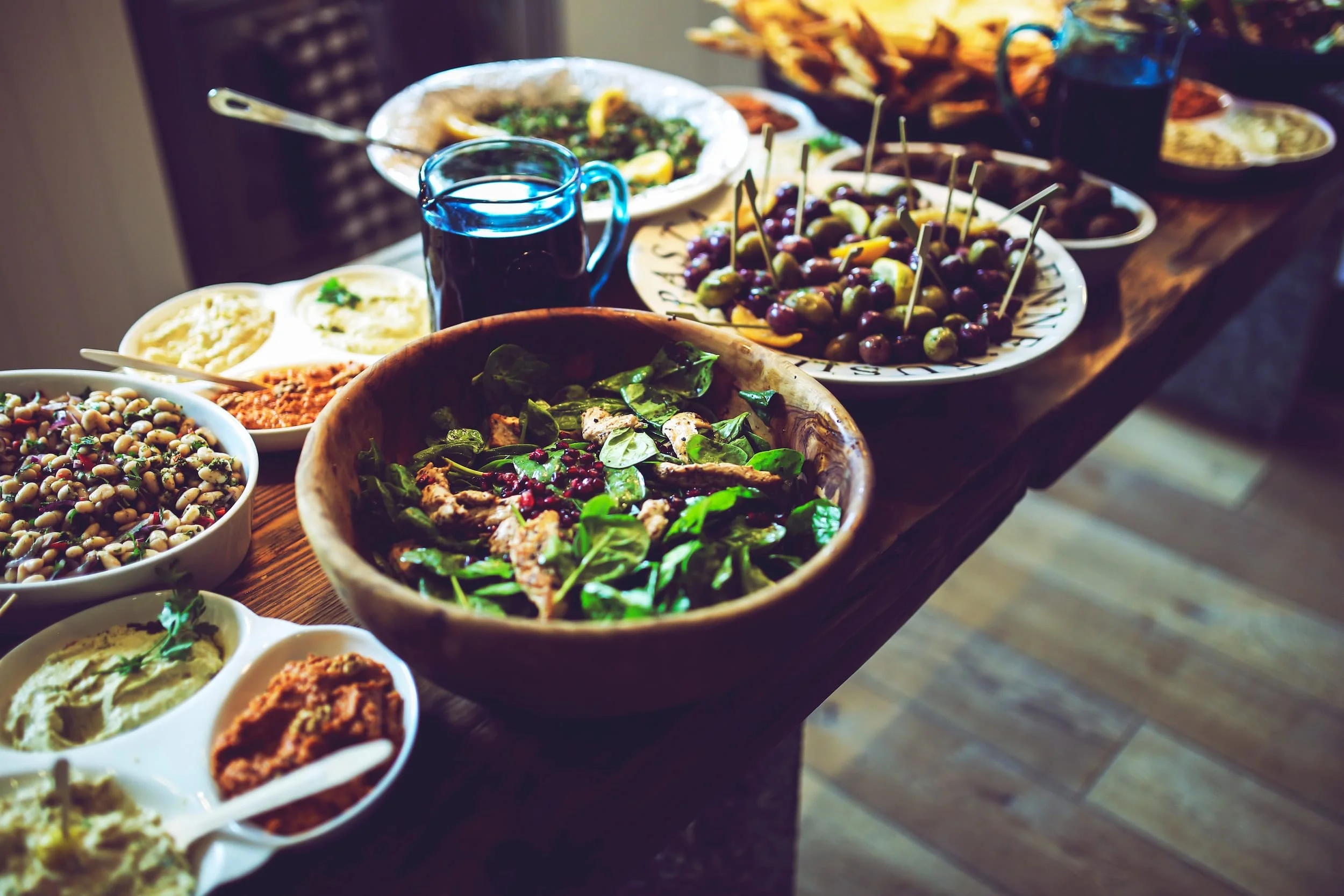 A delicious and colorful feast of vegan food sitting on a beautiful wooden table.