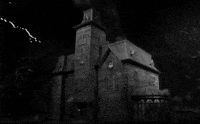 A haunted house being lit up by slashing lightning.