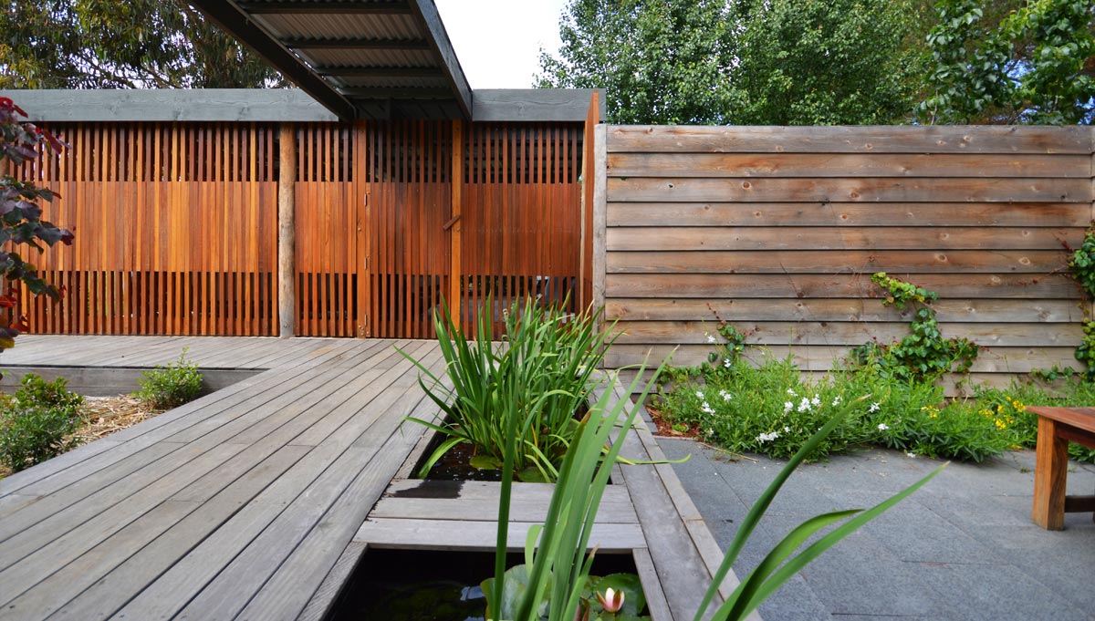 Geometric layout of timber deck over pond, paved area with bespoke timber carport screen and lap fence | Canberra Gardens