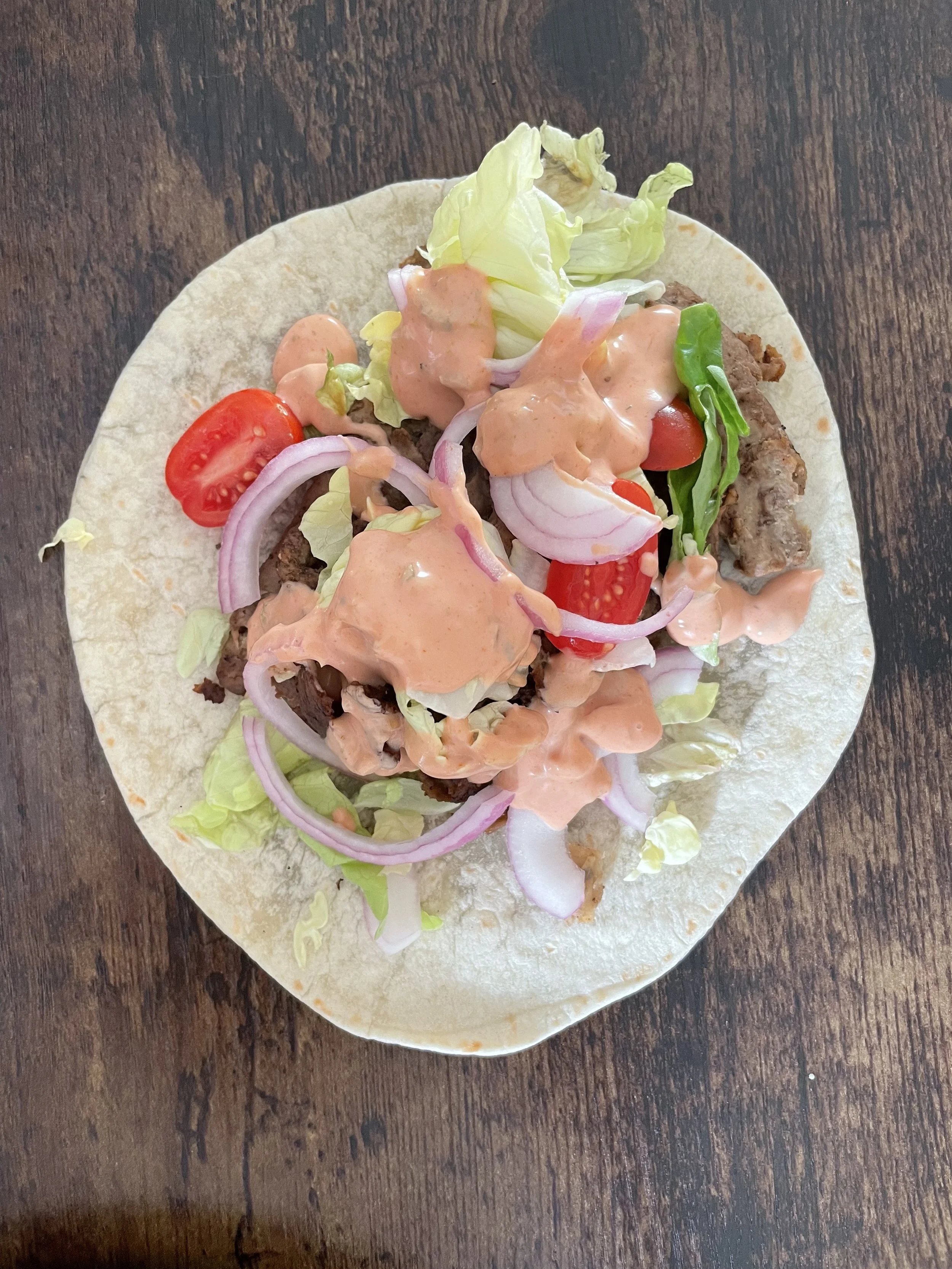 Salat, Tomaten, Zwiebeln und Sauce anrichten