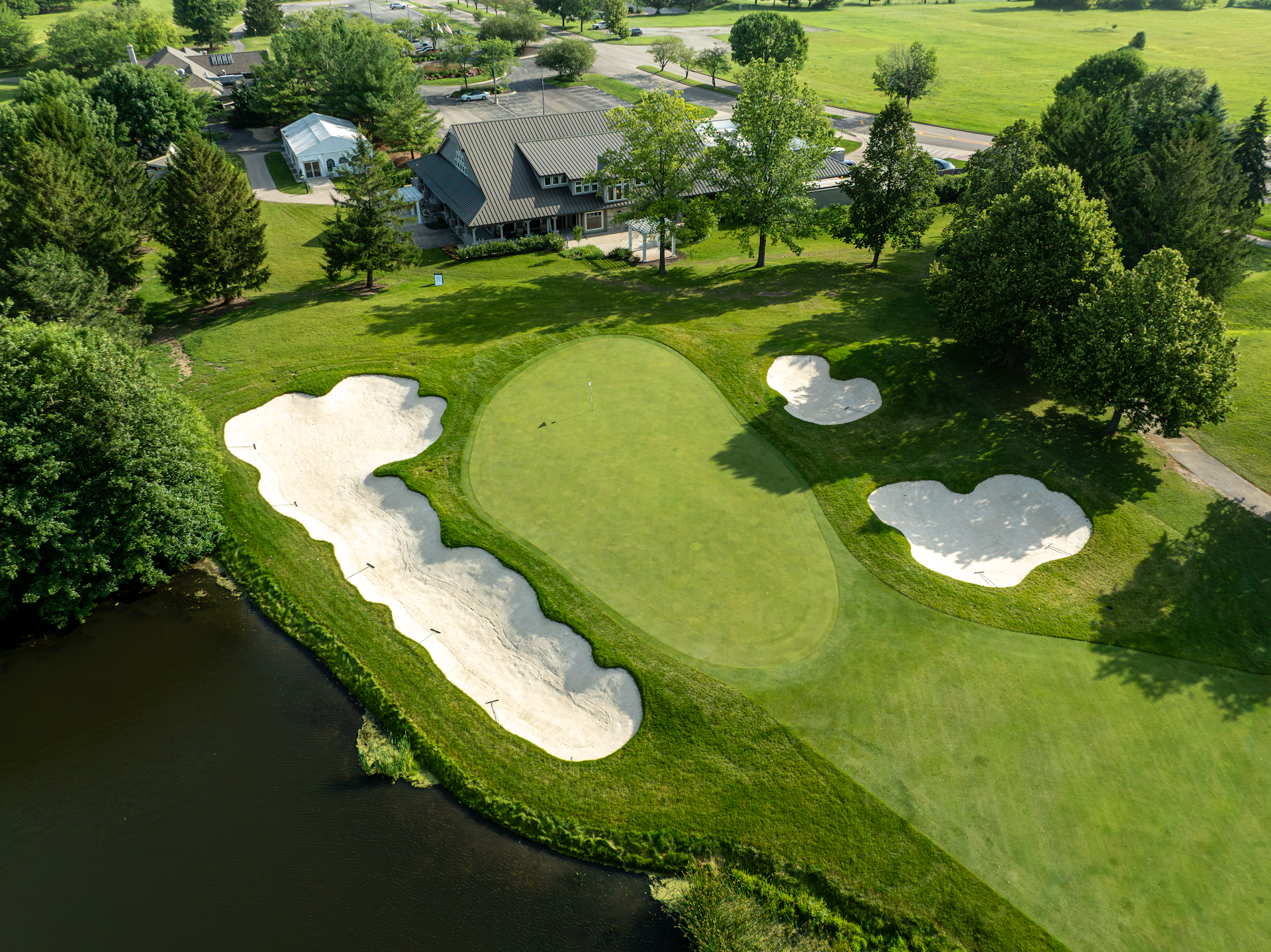 Aerial view of a golf course with sand traps, greens, water hazards, and trees in autumn colors.