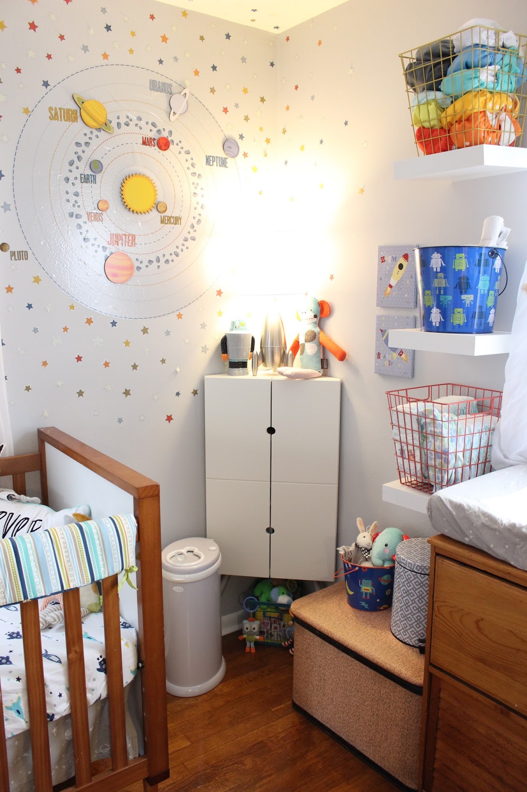 Decal: Target (Looks like it's no longer available. Love the way this looks but many of the stars are peeling off so I can't say I'd recommend it even if you can find it.) Corner Cabinet: Ikea PS 2014 Diaper Pail: Ubbi Trash Can: HomeGoods Robot Bucket: Target (was an Easter basket) Toy box: vintage Robot rattles: Lolli Living Robot bank: Target Rocket lamp: Pillowfort for Target Monkey: Petit Collage Rocket prints: WalMart Wire Baskets: Target Bunny Lovey: Ikea Leka Elephant Soother: Fisher Price Calming Vibrations Cuddle Soother
