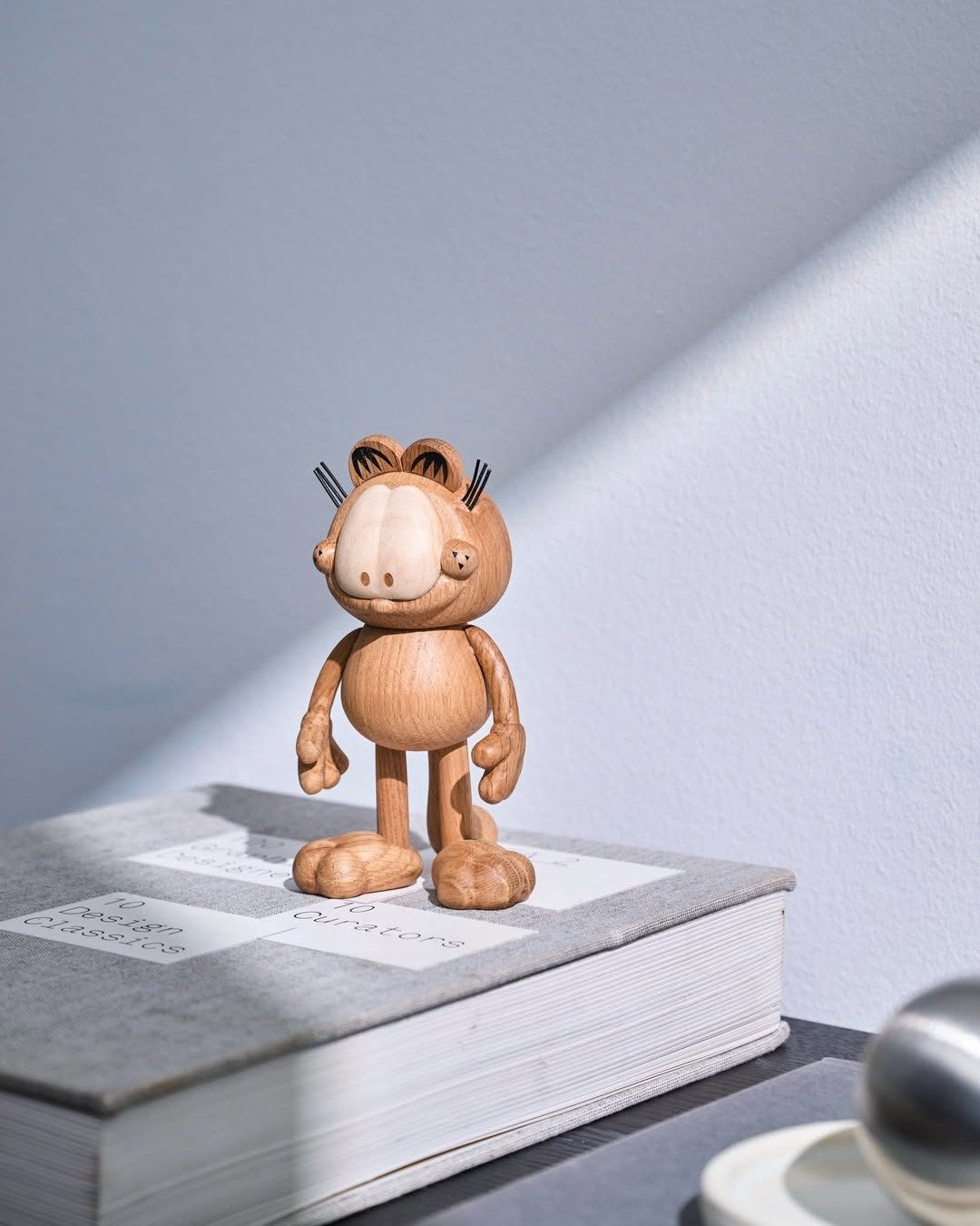 《ARTIFACTS - BOYHOOD》 
#加菲貓 #Garfield #丹麥品牌🇩🇰

BOYHOOD 由設計師兼創辦人 Jakob Burgs&oslash; 成立於丹麥，以天然橡木為材質，融合北歐極簡美學與精湛工藝，將玩具般的懷舊意象化為充滿詩意的擺飾。作品靜置於空間中散發溫度與故事感，喚醒人們內心深處的純粹與真摯的快樂。

加菲貓粉絲的夢幻收藏！
以實心橡木雕塑出加菲貓圓潤而立體的輪廓，搭配黑色細節勾勒經典表情與條紋，讓大家熟悉的幽默形象更添一份質樸的高級感，是居家空間中最具靈魂