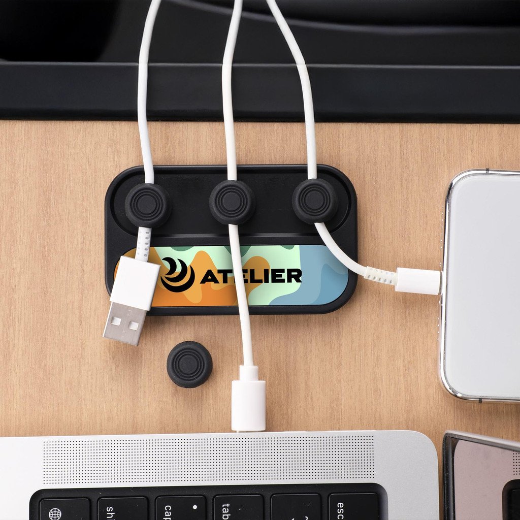 Multiple charging cables connected to a power strip on a wooden desk, with a laptop, a tablet, and a smartphone nearby.