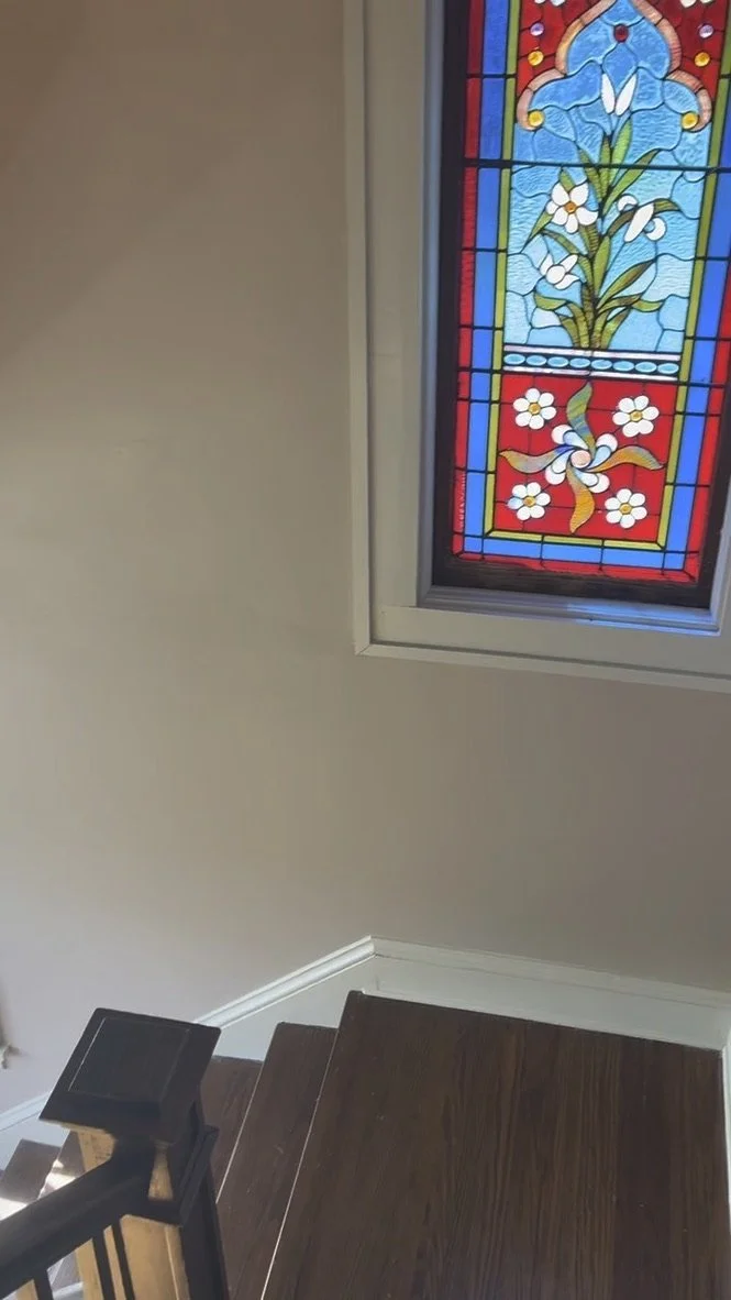 Stained glass window with flowers above the stairwell of the therapy offices