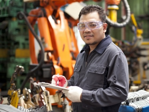 Technician++engineer+holding+a+notepad+with+robot+machine+on+background.jpg