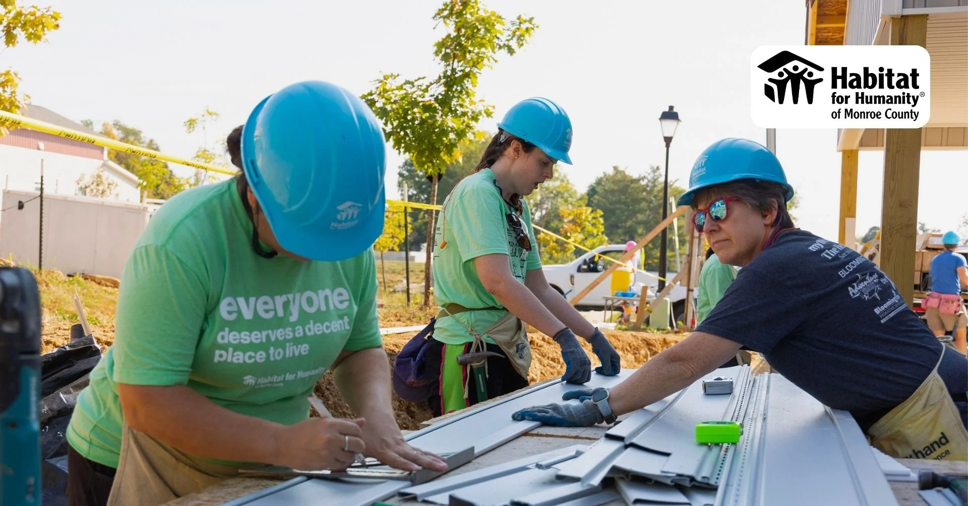 Three volunteers from Habitat for Humanity take measurements for a construction project.