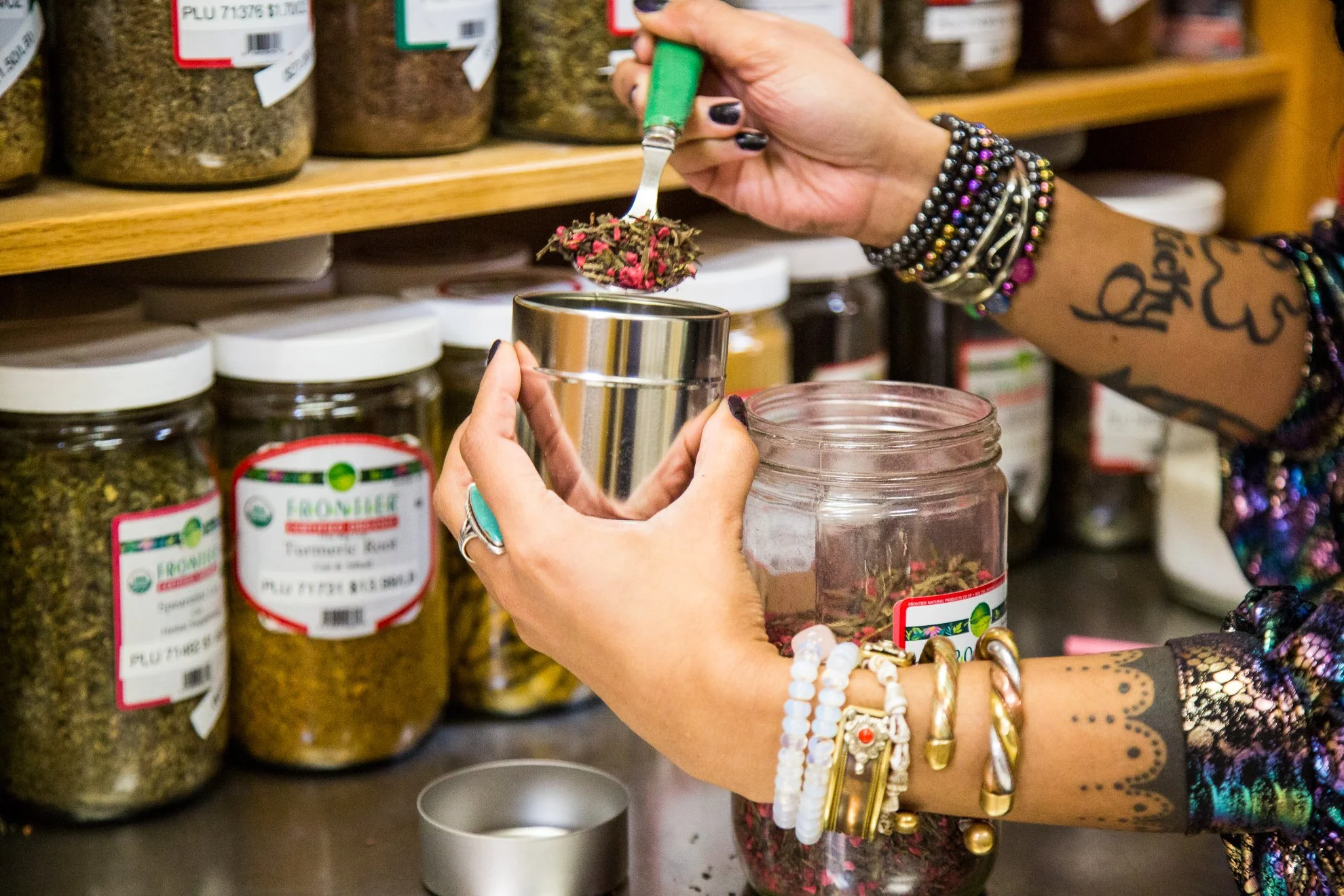 Person putting bulk herbs in a reusable container from our bulk section