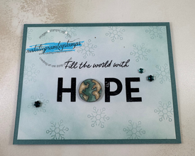 Greeting card with green perimeter and a pale cover that says Fill the World With HOPE. The O in hope is a picture of the globe.