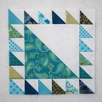 Lost Ships Quilt block with a large half-square triangle piece in the center with smaller triangles surrounding it on all four sides