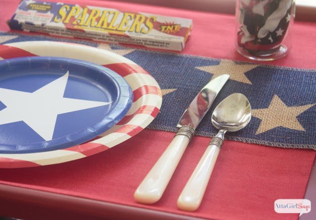 A place setting with red white and blue plates, utensils and placemat