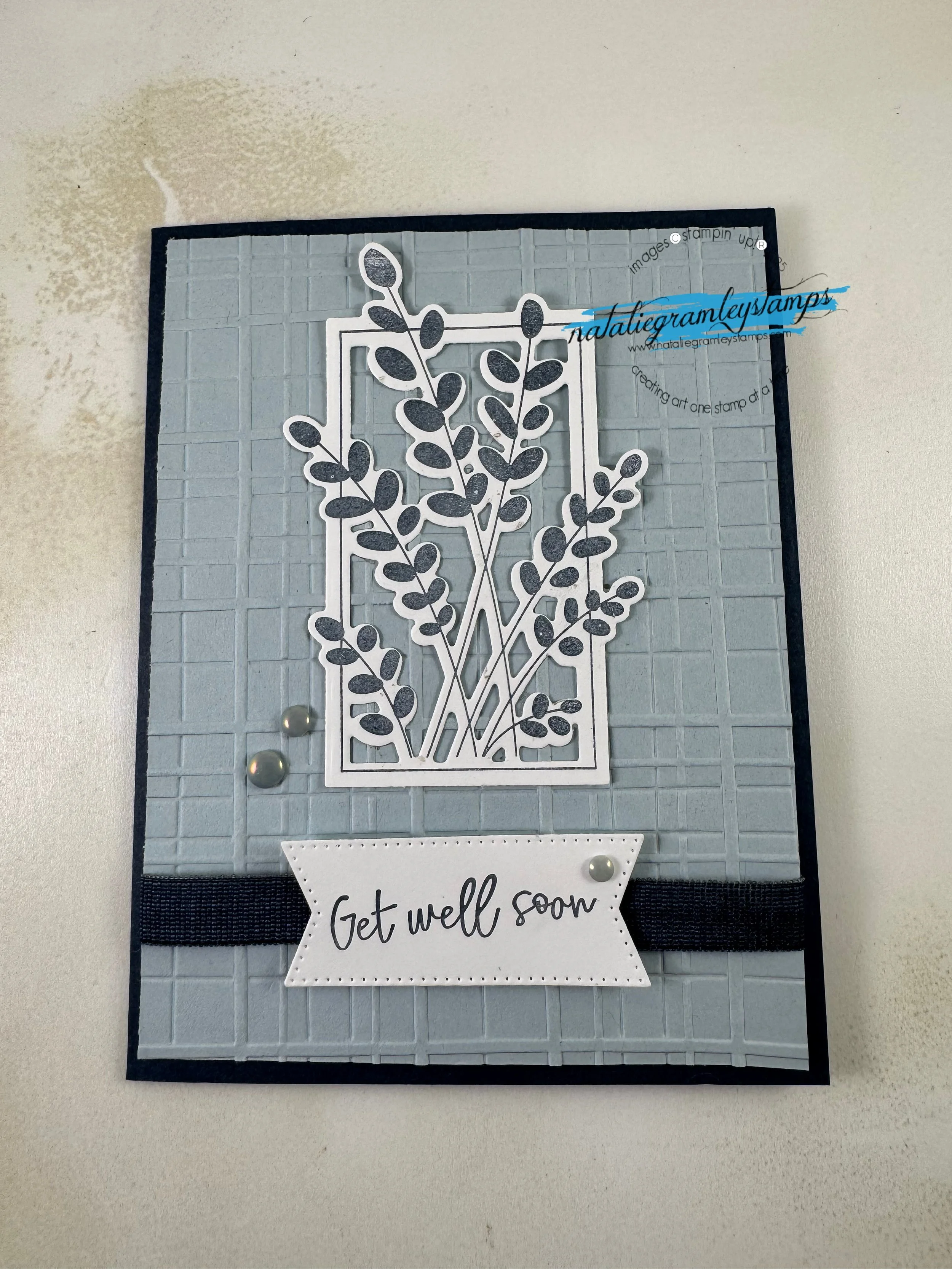 A greeting card with tall floral sprays in gray and a message of Get Well Soon