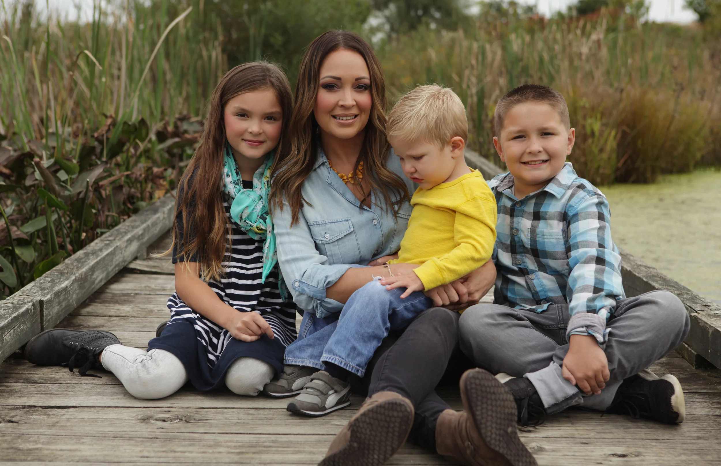 golden light mother and three children on a bridge overlooking a pond