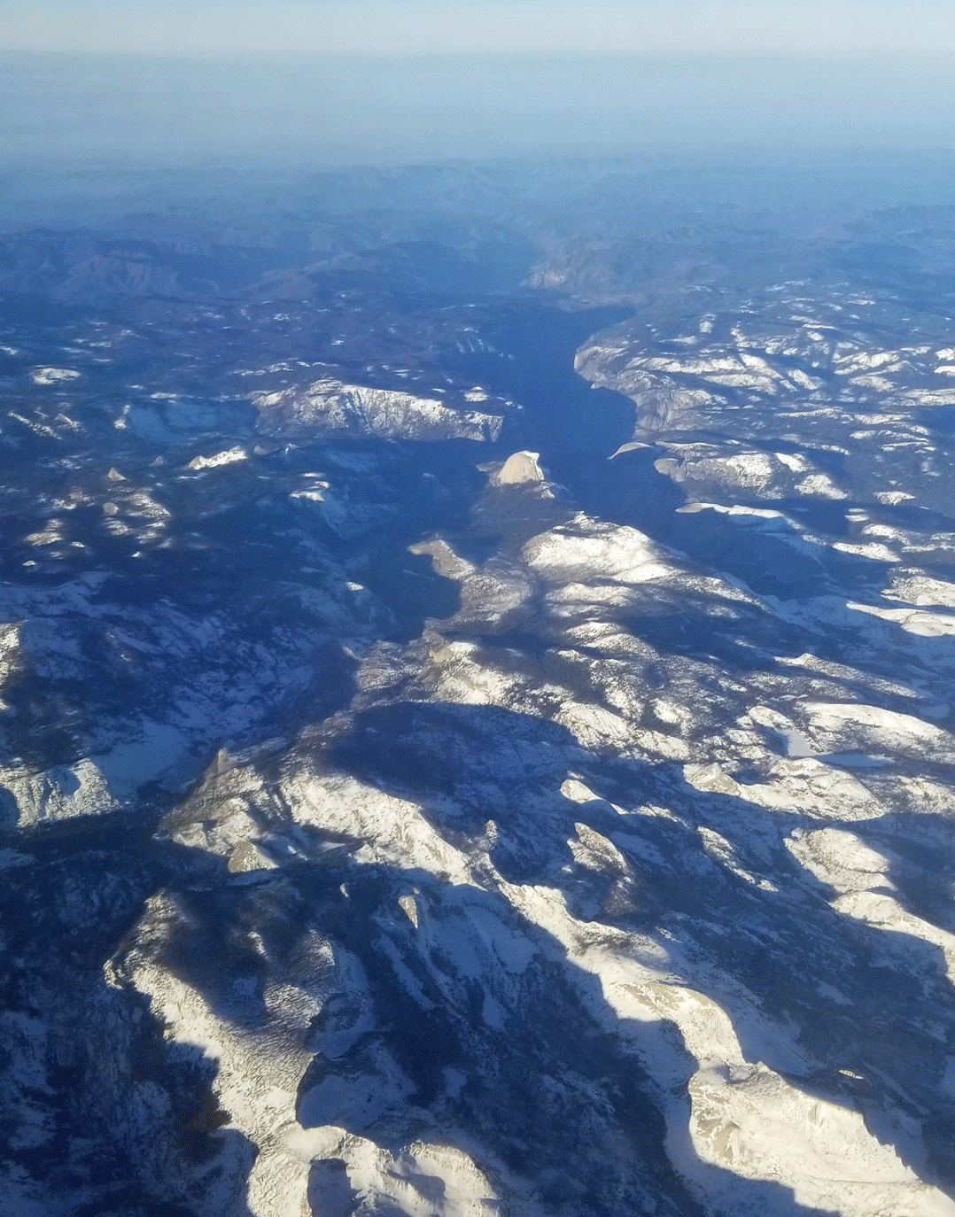 View to west across the high Sierra toward the deeply shadowed Yosemite Valley. Half Dome is prominent.