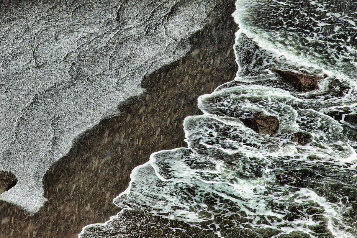 Snow and surf on the black sand beach.