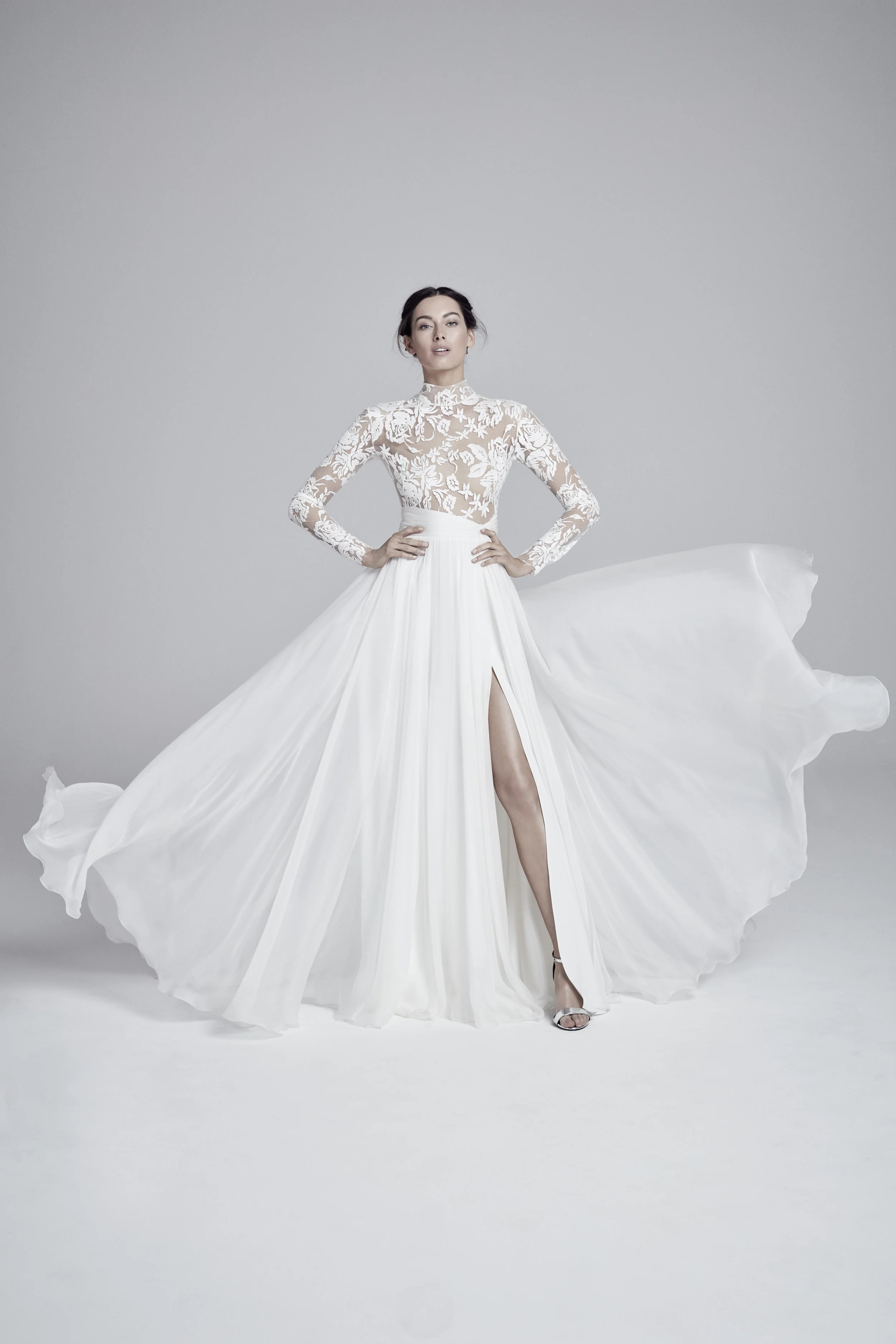 LUELLA Long sleeved and high neck bodice with large lace embroidery. The flowing silk skirt features a thigh-high slit .