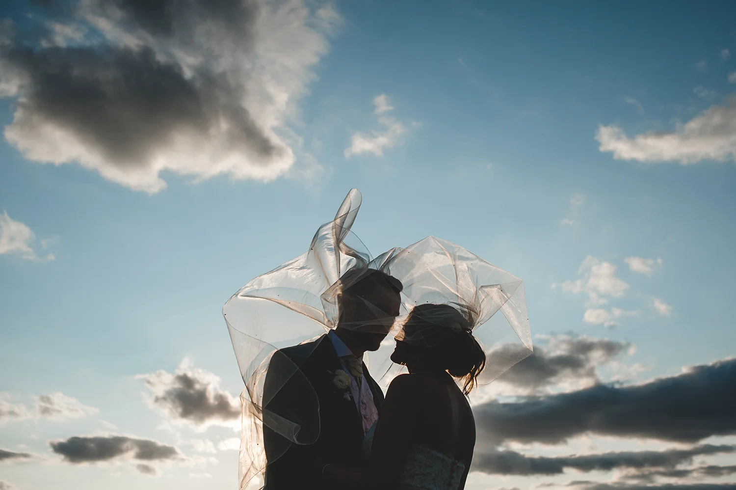 JMA-Photography-silhouetted-wedding-couple-under-flying-veil.jpg