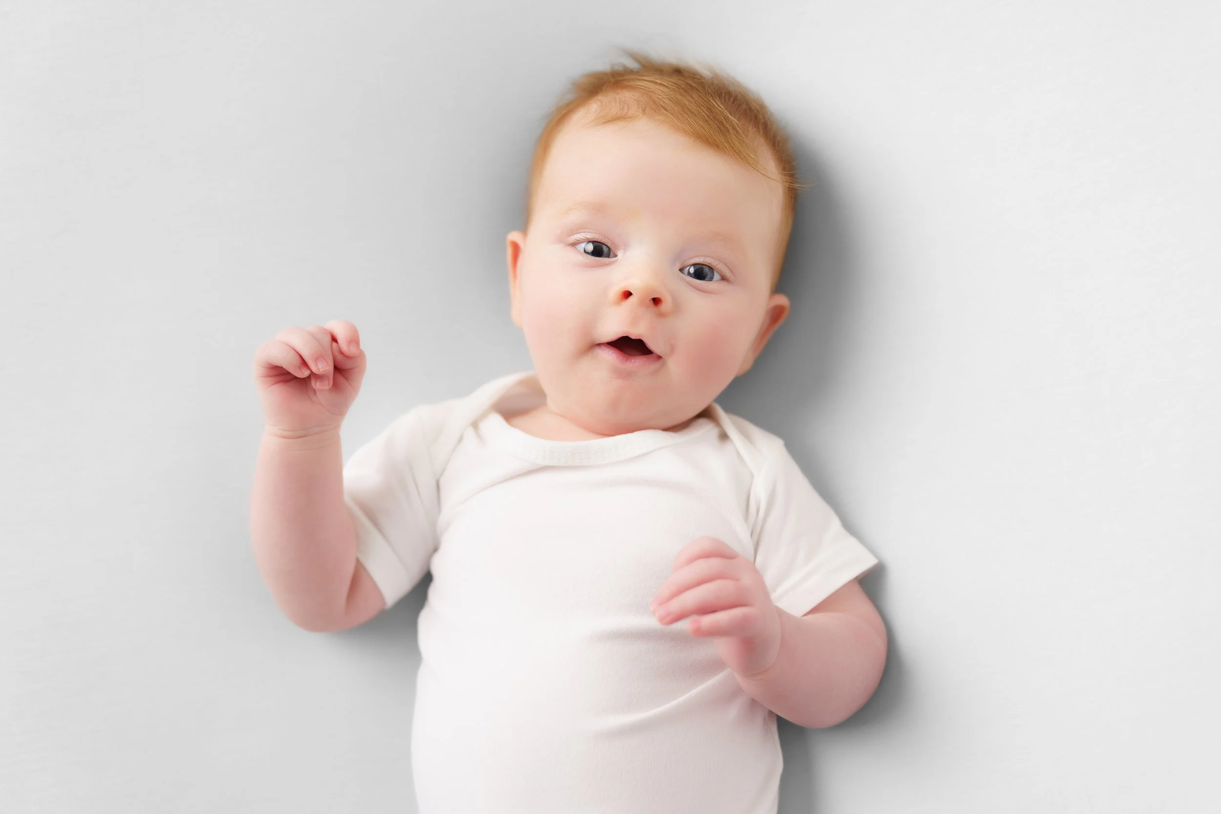 roodharige baby lacht op een witte achtergrond