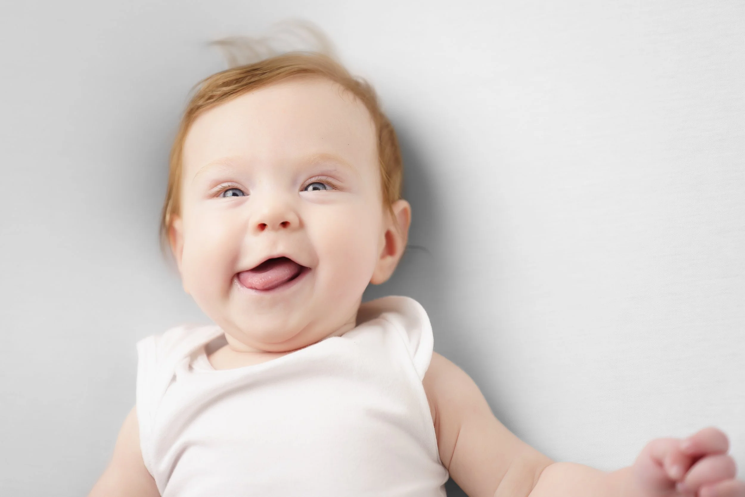 Baby lacht met tong uit de mond op witte achtergrond