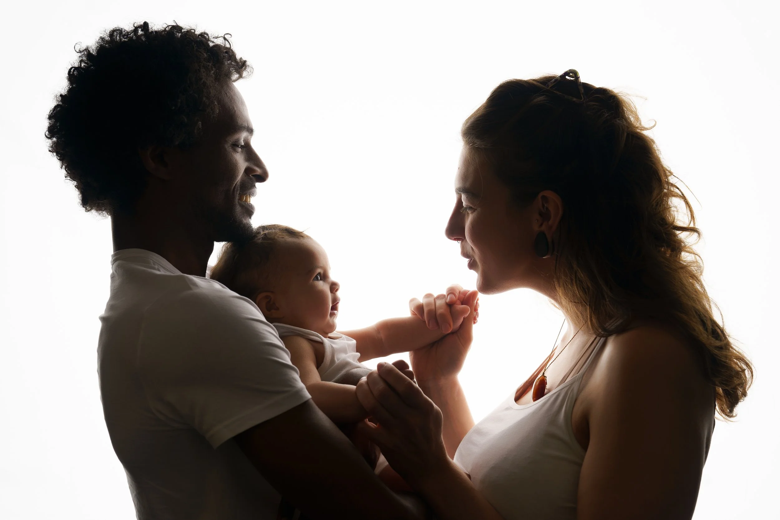 Een koppel in tegenlicht tijdens een zeer mooi moment met hun baby