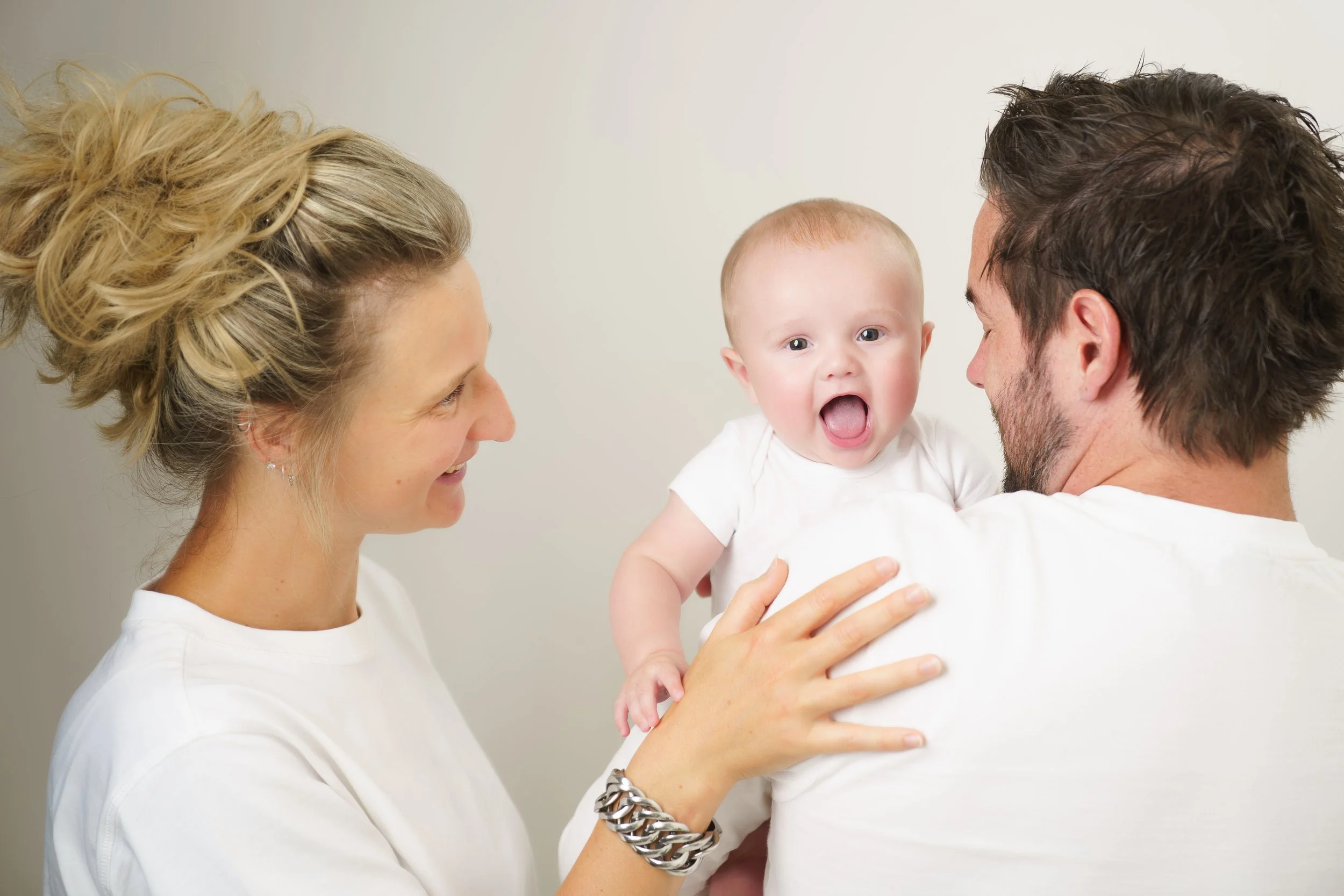 Twee ouders staan dicht bij elkaar met hun baby in een rustig moment.