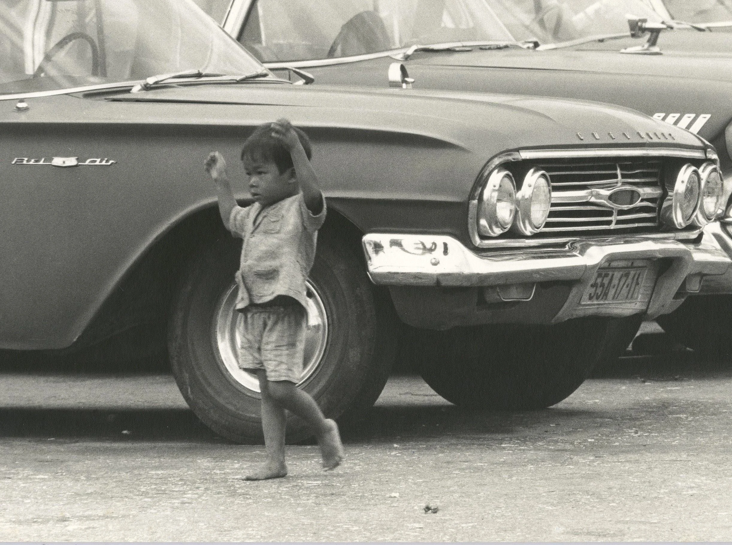 Photo 9: A “street child” wandering past abandoned Chevrolets in Ho Chi Minh City. Photo by author.