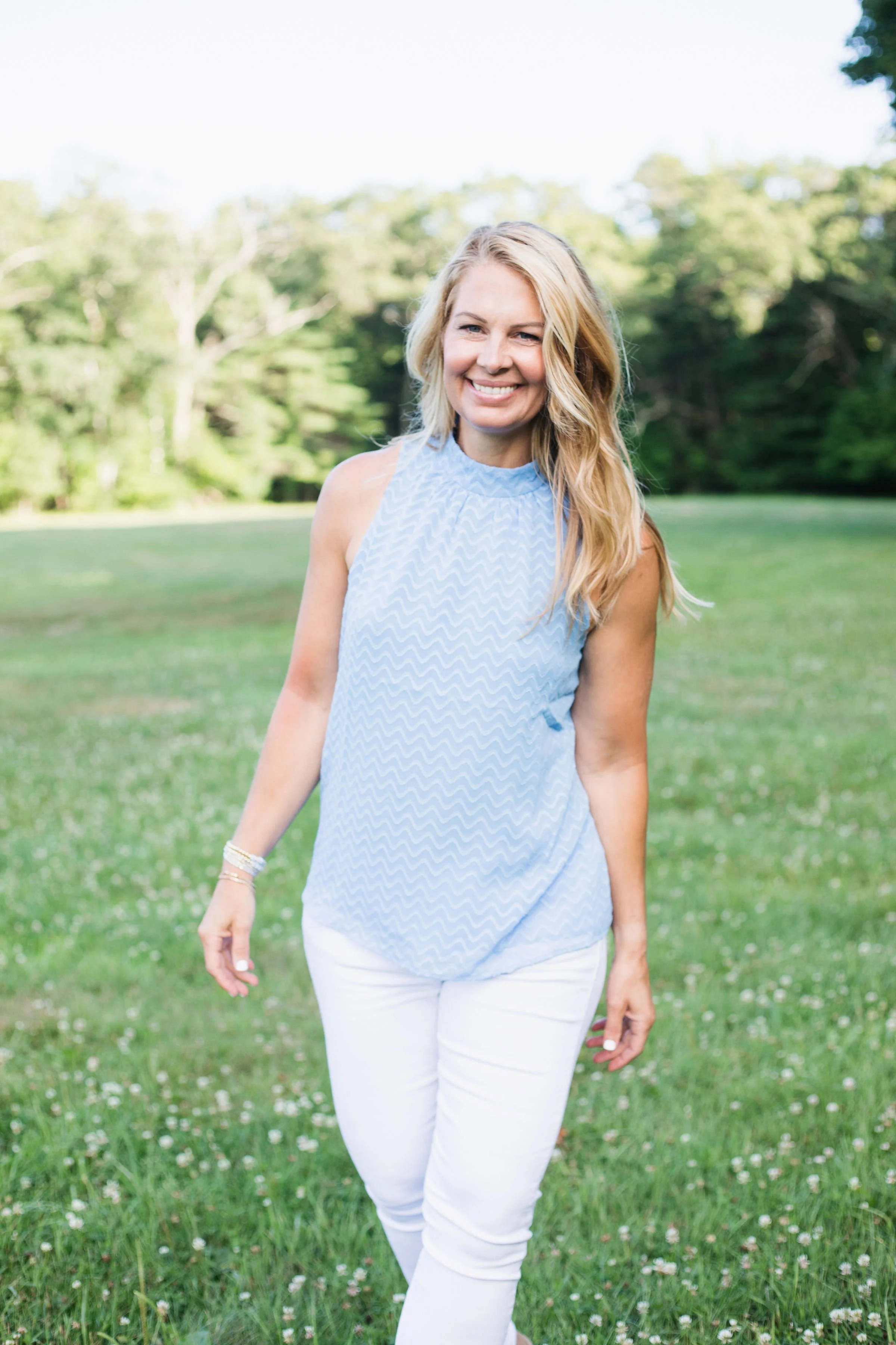 Angie Bloom with blue top talking about energy healing and a beautiful background of green and blue top