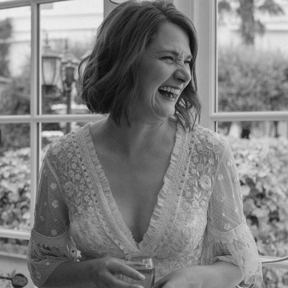 vicky on her wedding day, looking like pure sunshine.
﻿﻿
﻿﻿(image description: a black and white photograph of a woman on her wedding day. she's laughing while her husband reads his speech, looking to her friends out of shot, happiness all across her