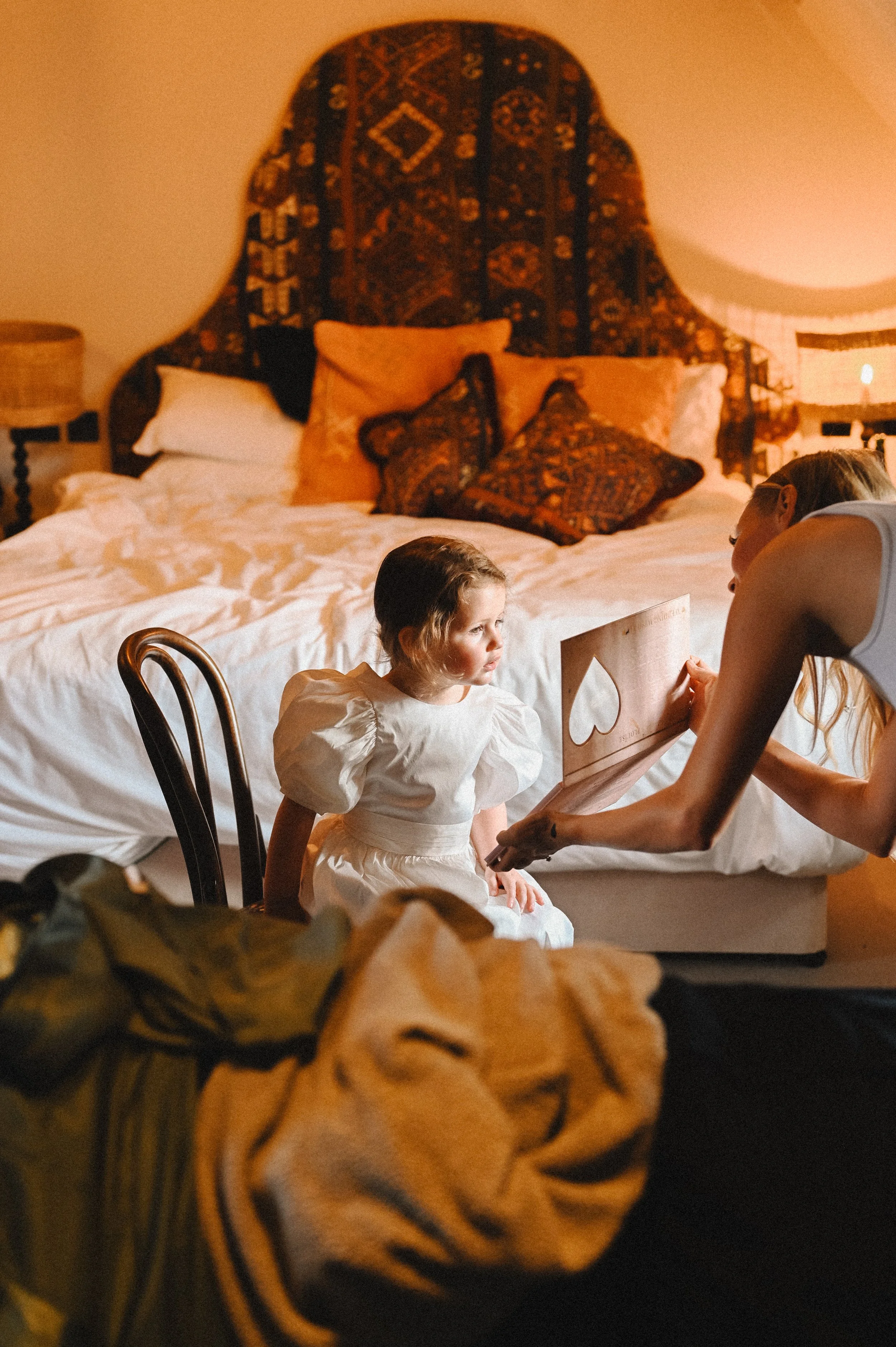 A colour photograph at The George and Dragon of a white girl, a flower girl being shown her reflection by a make up artist.