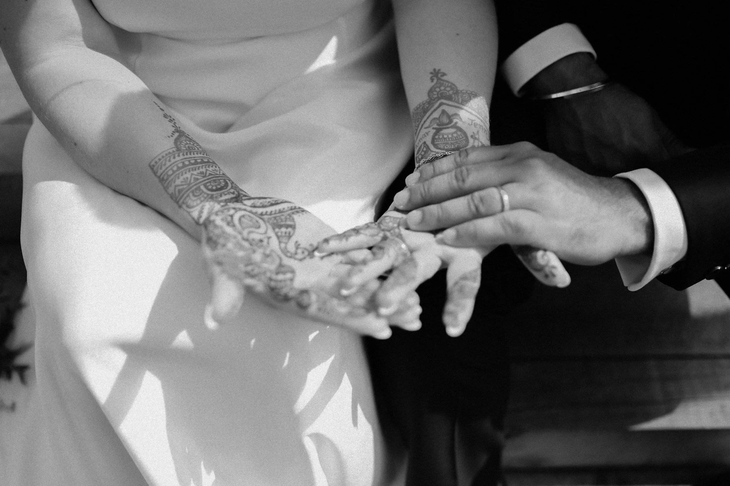 A black and white photograph at The Crescent Turner of a Brown man and white woman, a bride and groom holding hands. You can see all the detail of the bride's Mendhi.